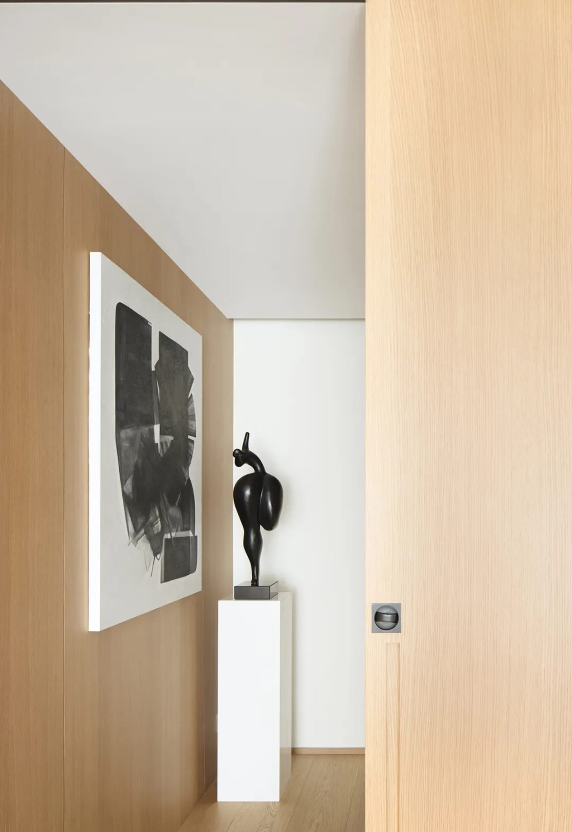 Modern minimalist interior with wooden walls, white column, and abstract black and white painting.