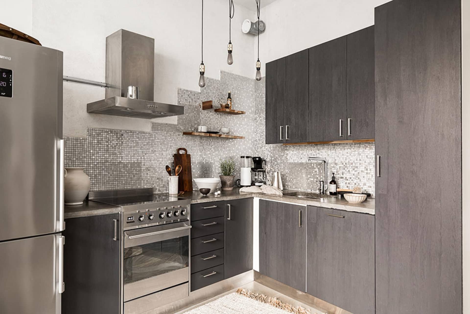 Modern kitchen featuring a stone backsplash with stainless steel appliances and dark cabinets.
