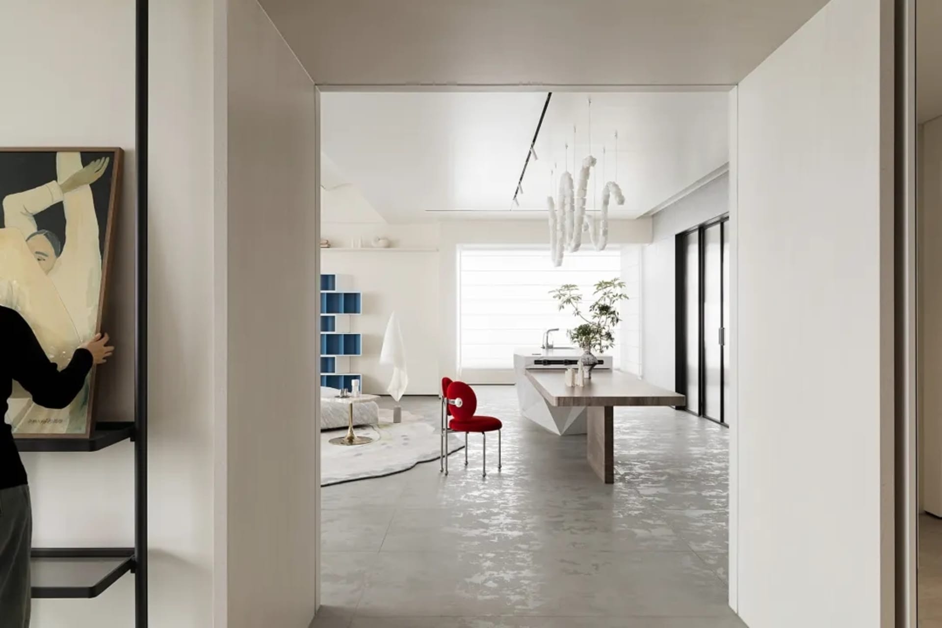 A modern living space with concrete floors, minimalistic decor, and a red chair.