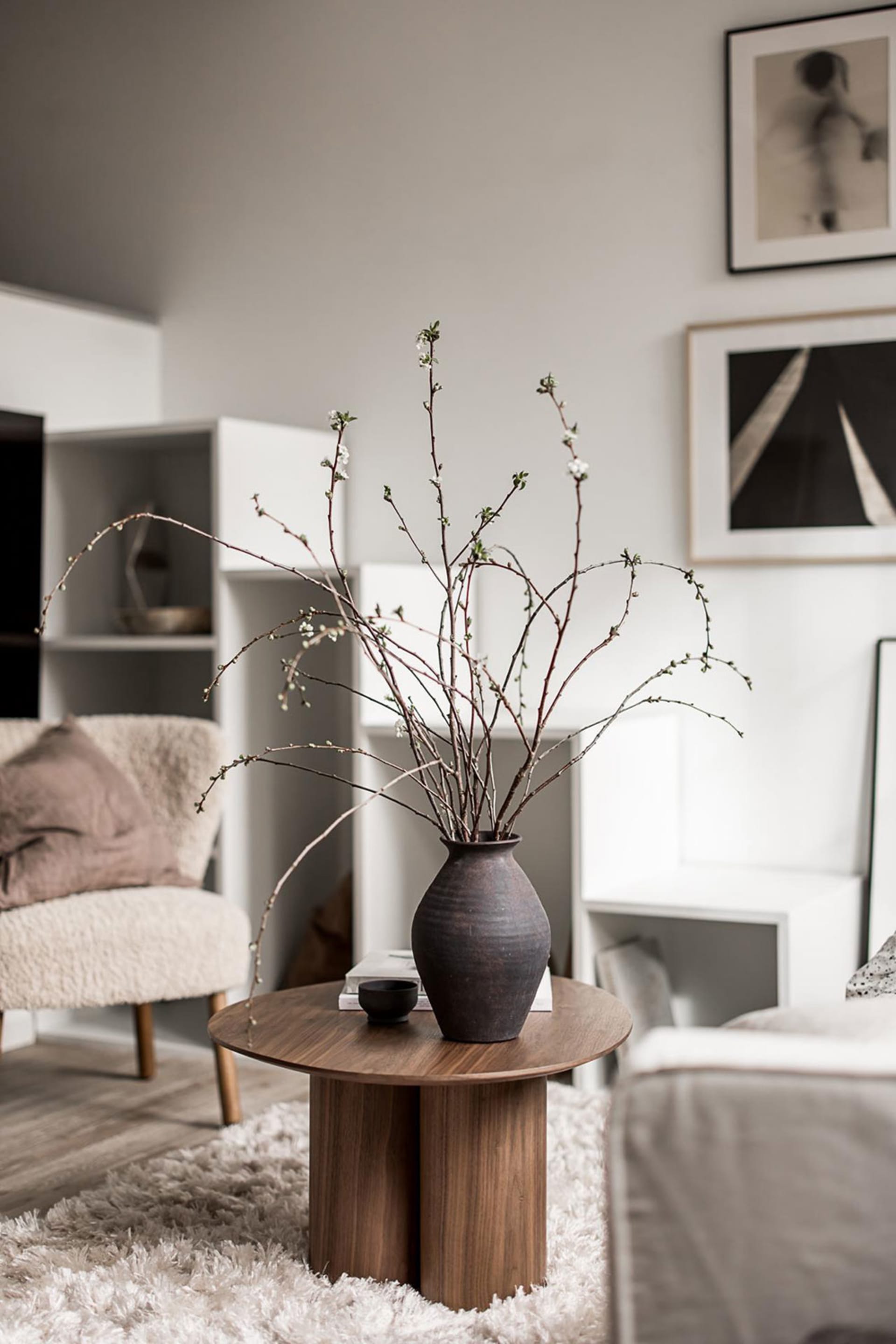 Scandinavian-style living room with modern furniture, minimalistic decor, and a vase of twigs on a wooden table.