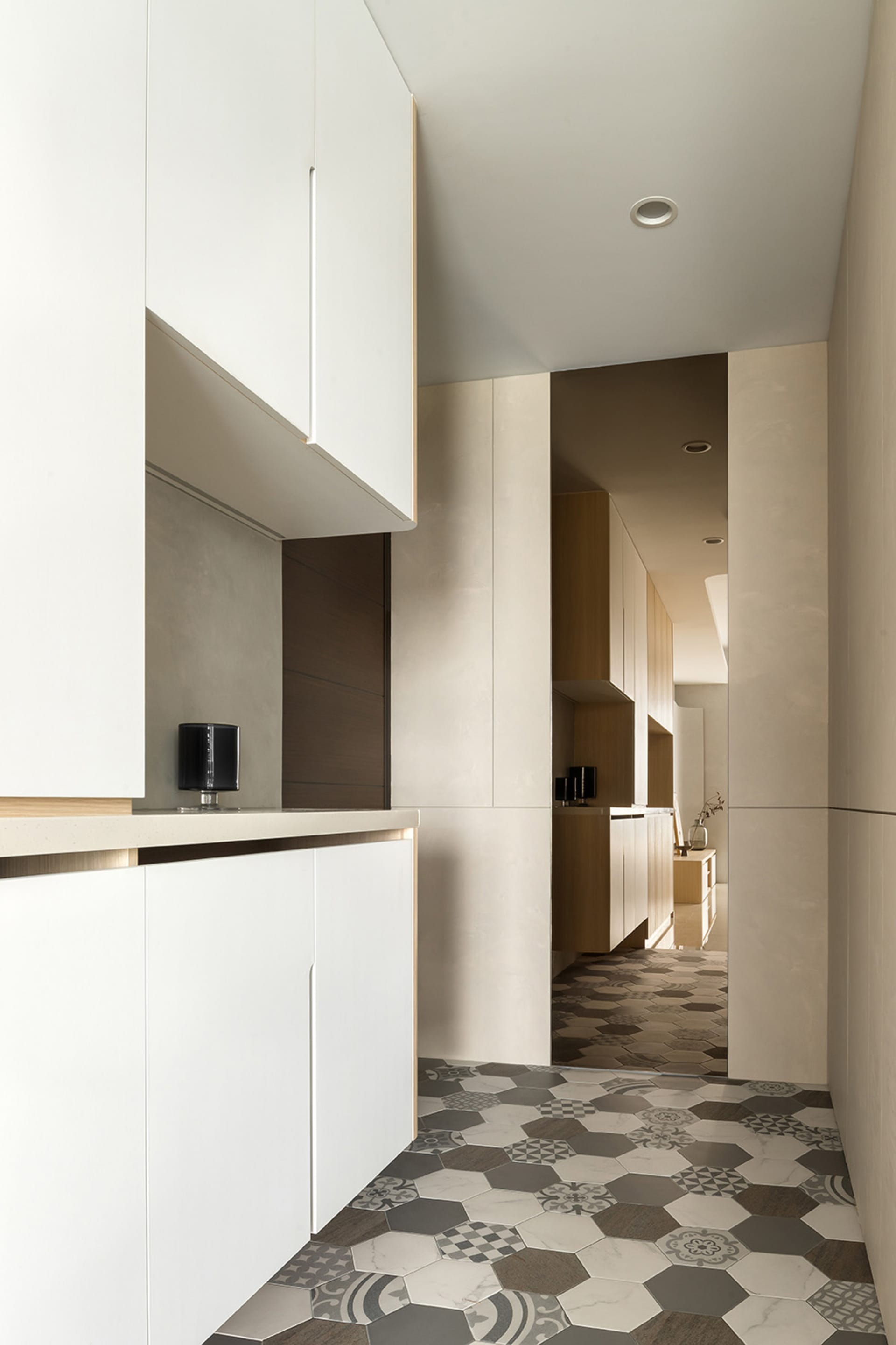 Modern residential kitchen with minimalist design, white cabinets, and marble walls