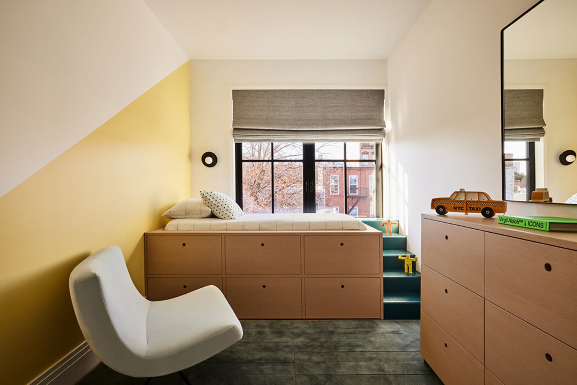 A modern bedroom with a wooden bed frame, white chair, and a window with gray curtains.