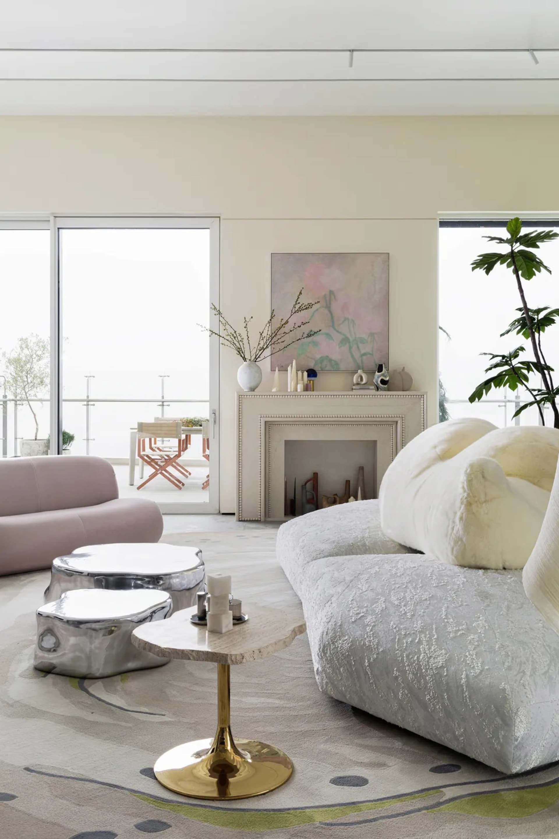 Modern living room with minimalist furniture, large windows, a fireplace, and a plant.
