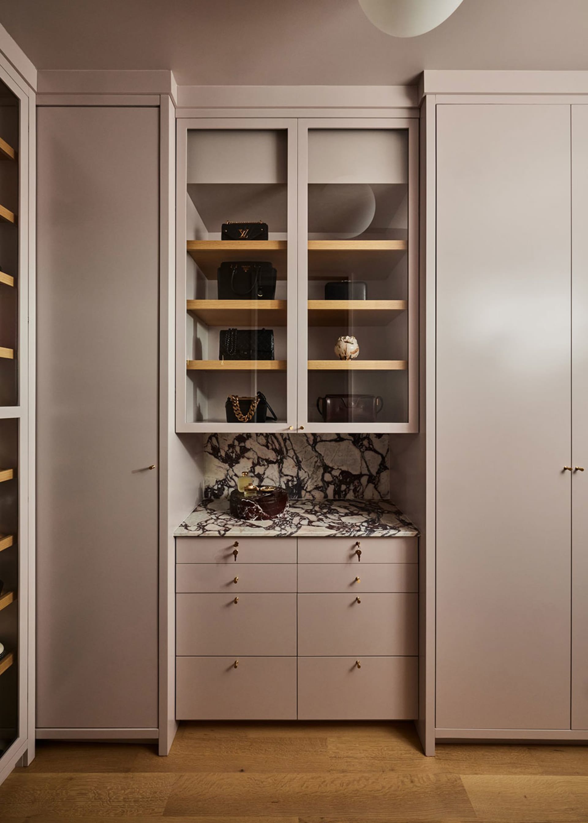 A minimalist wardrobe with glass shelves, marble countertop, and wooden drawers.