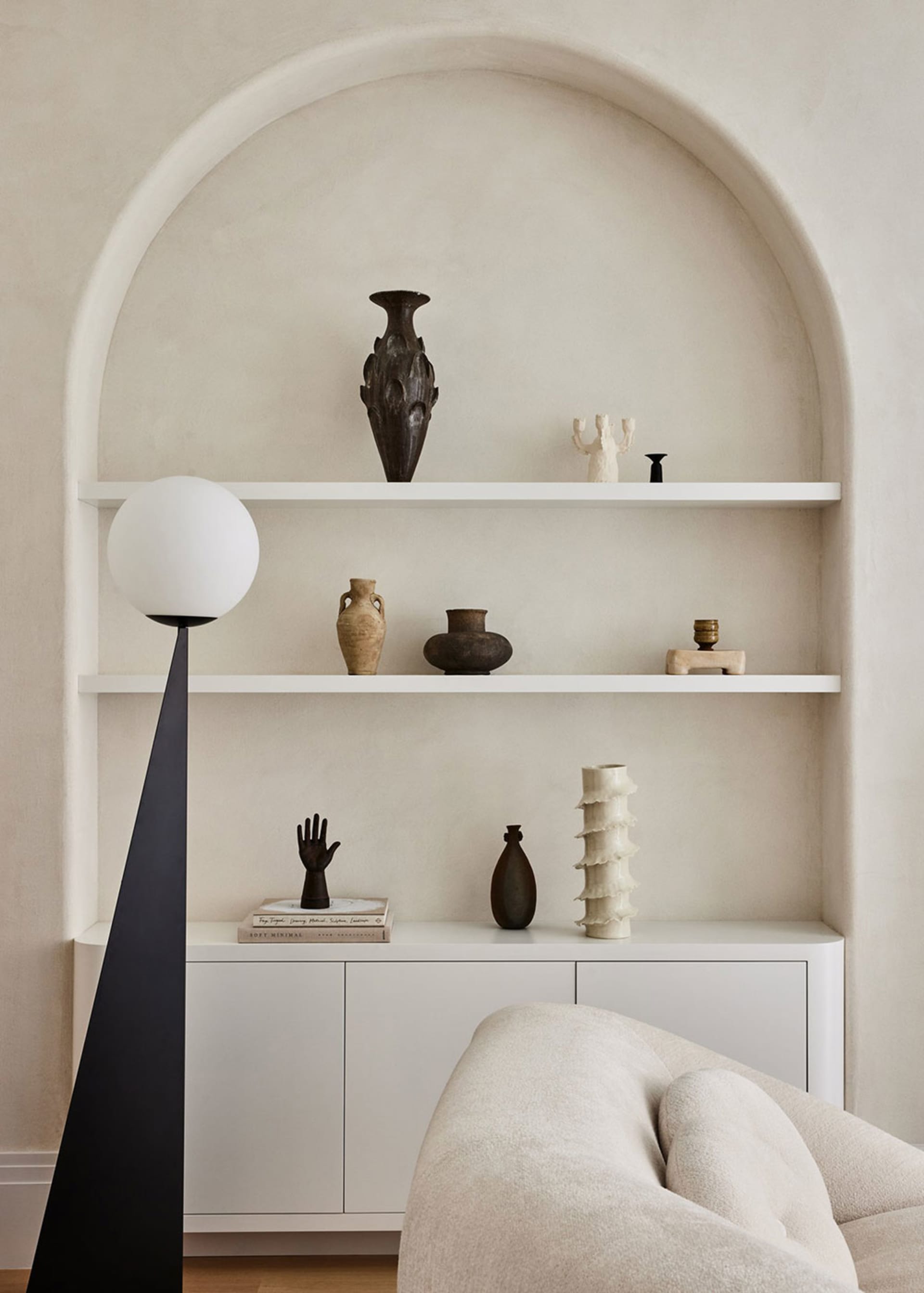 A minimalist living space featuring concrete shelving and ceramic decorations.