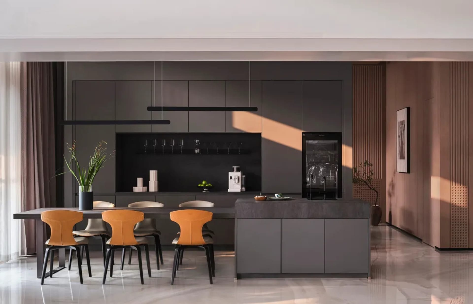 Modern minimalist kitchen featuring black cabinets, white marble countertops, and orange chairs.