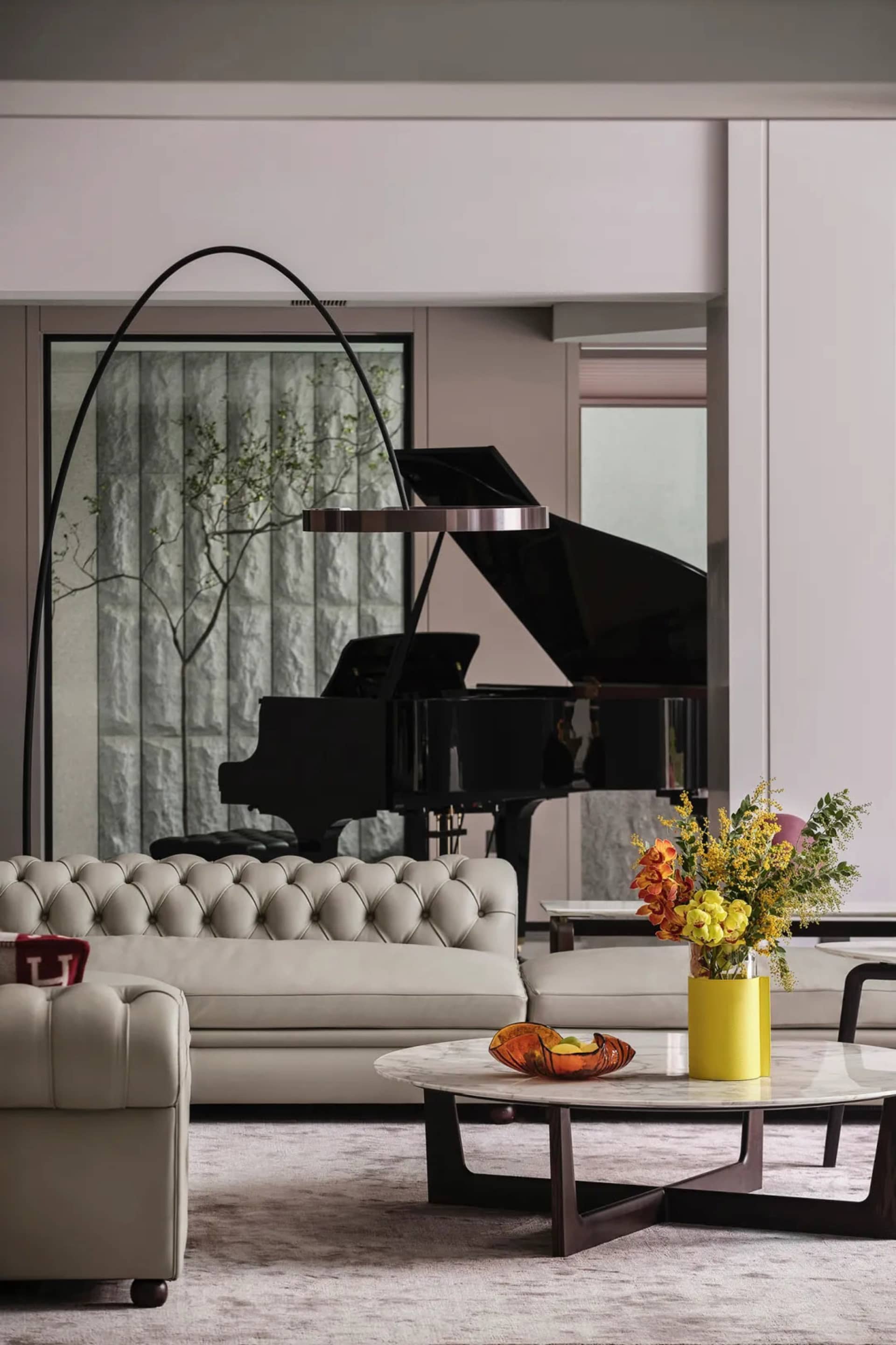 A minimalist living room with leather furniture, a round marble coffee table, and a tall floor lamp.