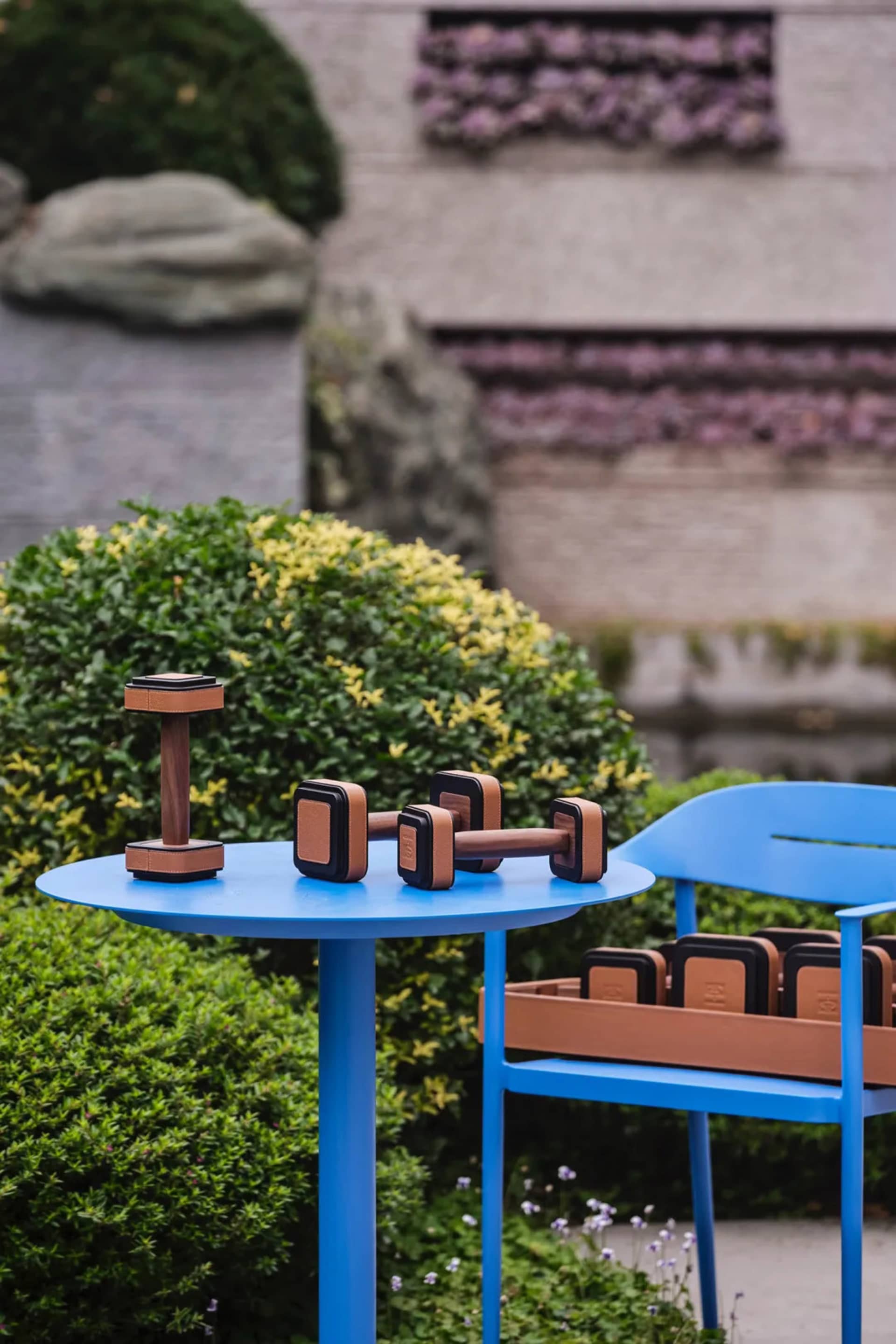 Outdoor furniture featuring metal and leather with dumbbells on a blue circular table and blue chair.