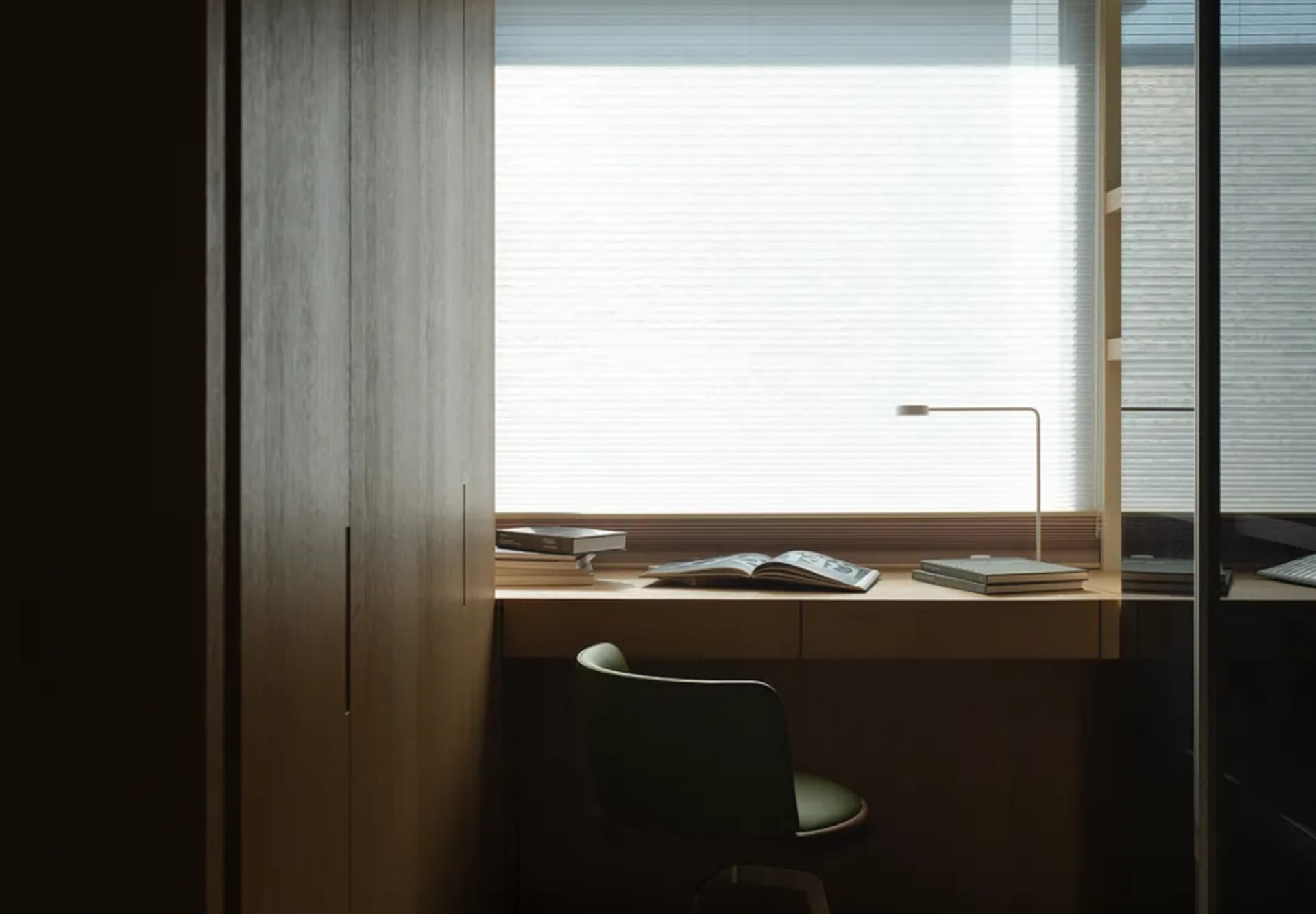 Minimalist office with a window view, wooden desk, and simple design elements.