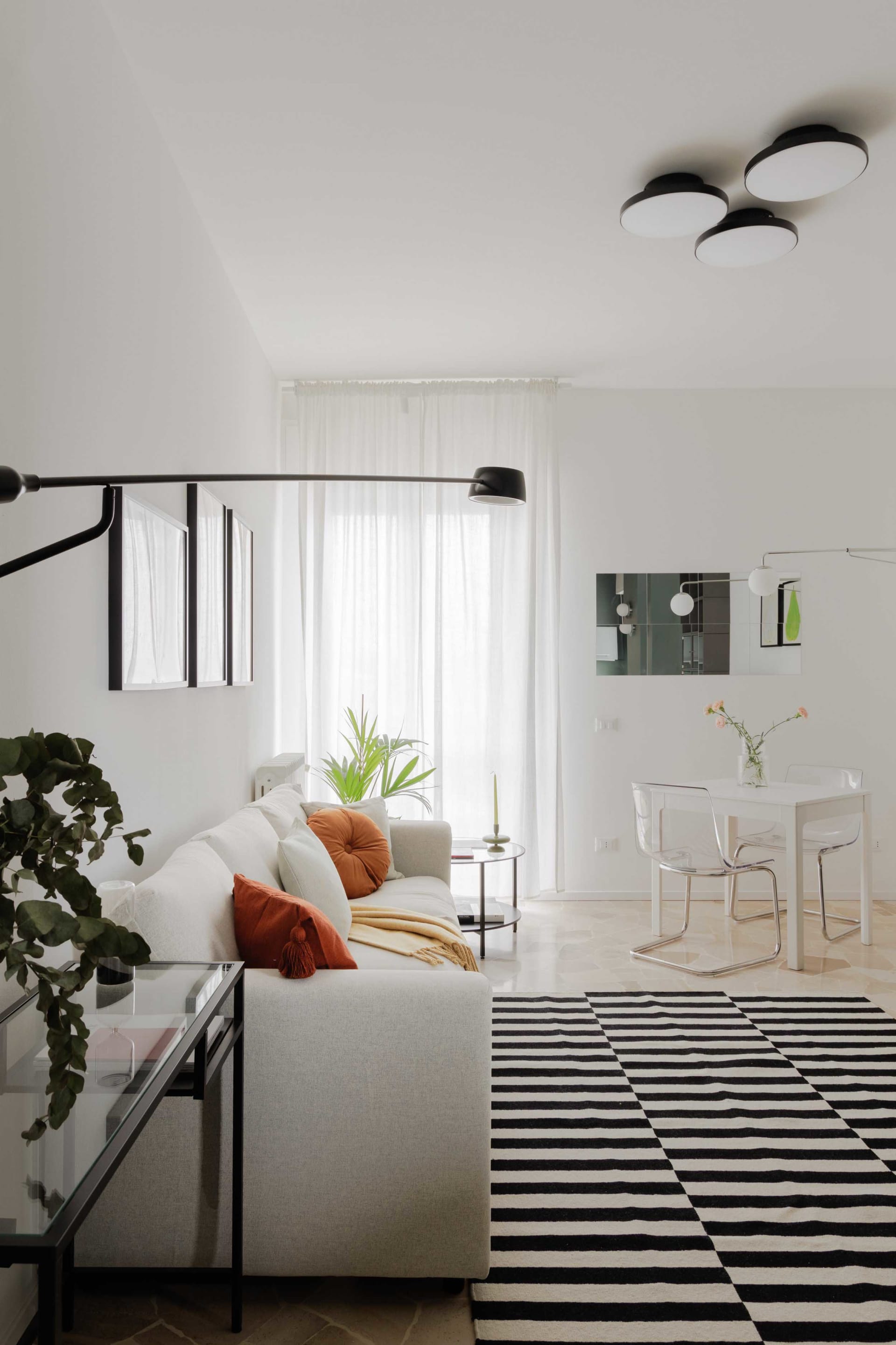 A minimalist living room featuring concrete furniture and a black and white striped rug.