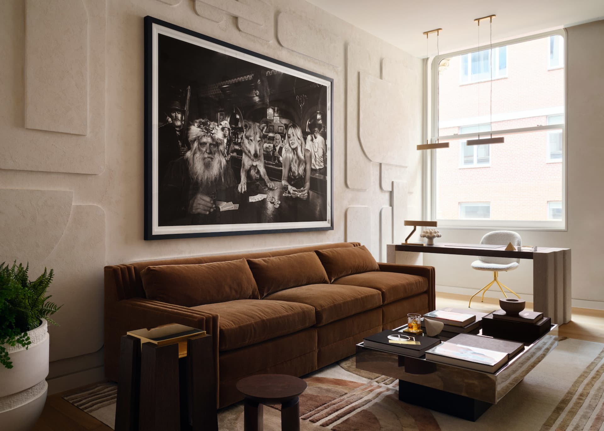 A modern living room featuring a brown velvet sofa, a large framed photograph on the wall, a coffee table with books and a dr