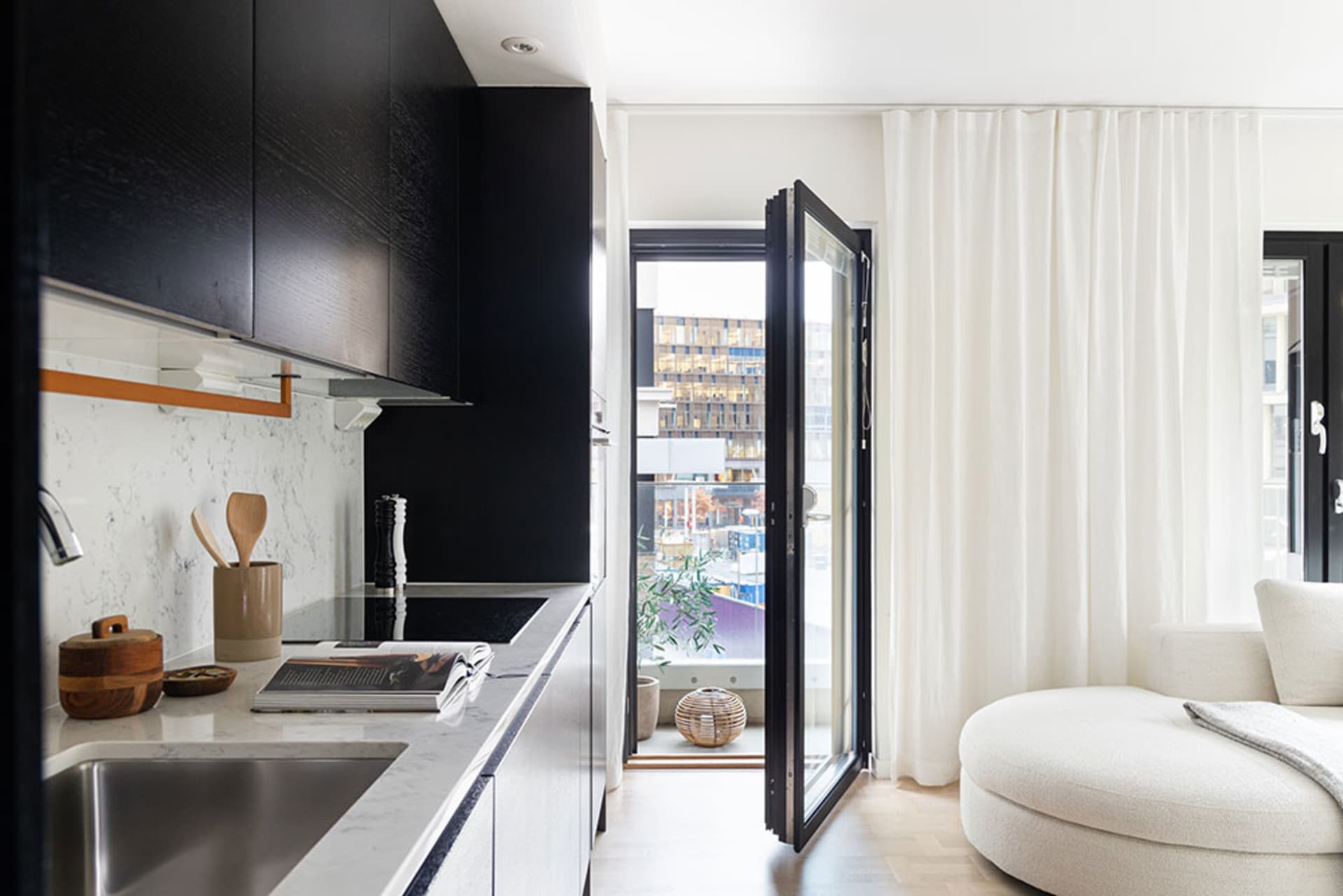 Minimalist kitchen featuring marble countertops, black cabinetry, and wooden accents