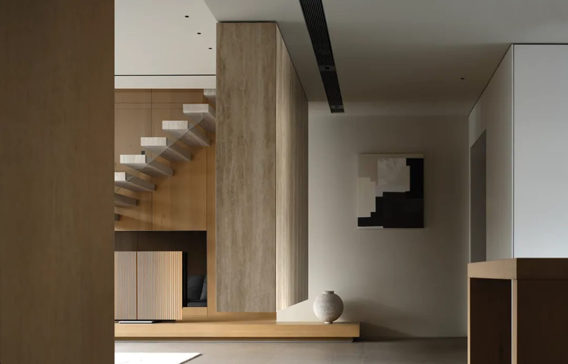 Modern minimalist living room with light-colored wooden walls and furniture, grey sofa, and grey floor.