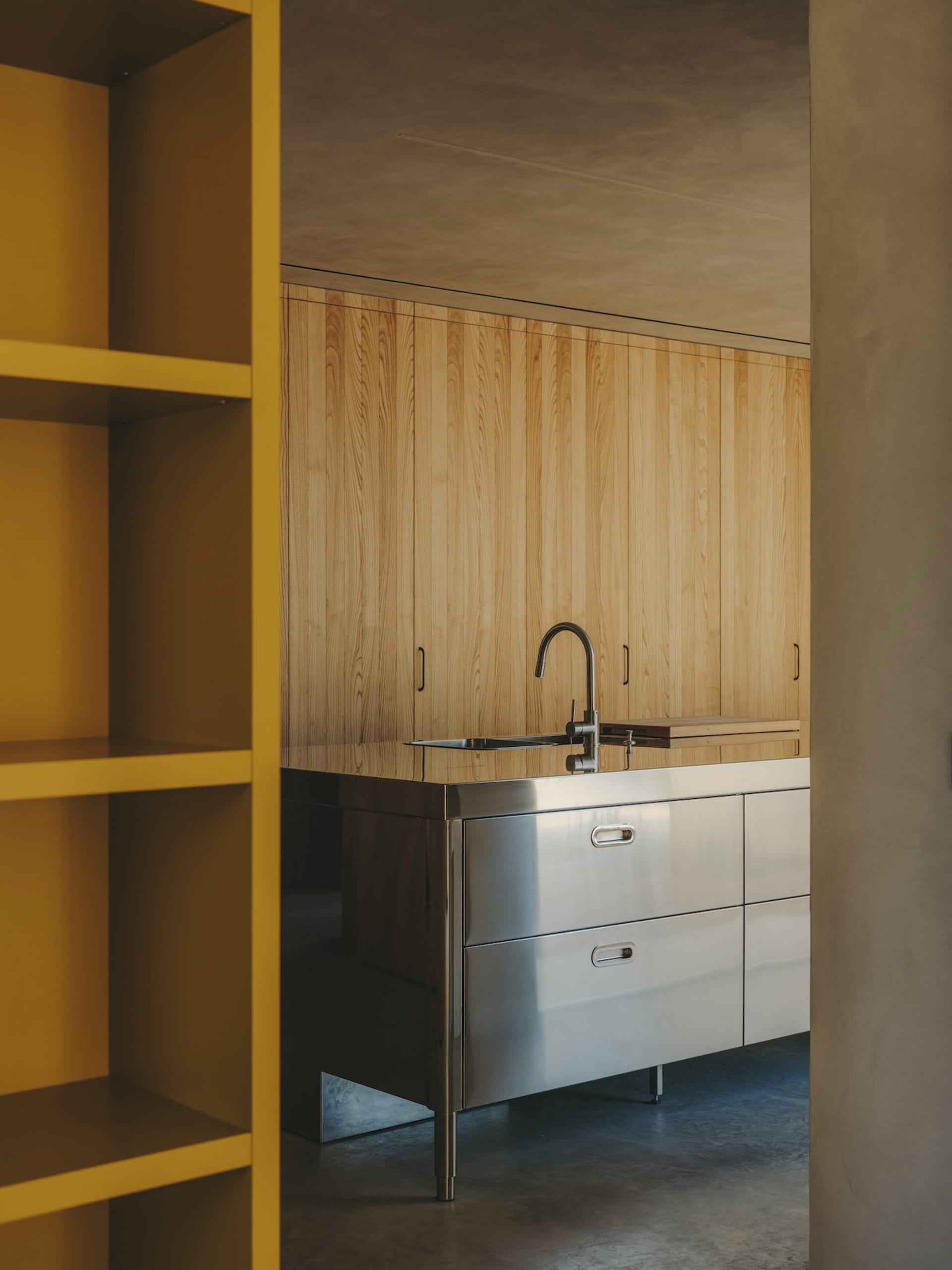 A minimalist kitchen featuring wooden cabinets and a stainless steel countertop.