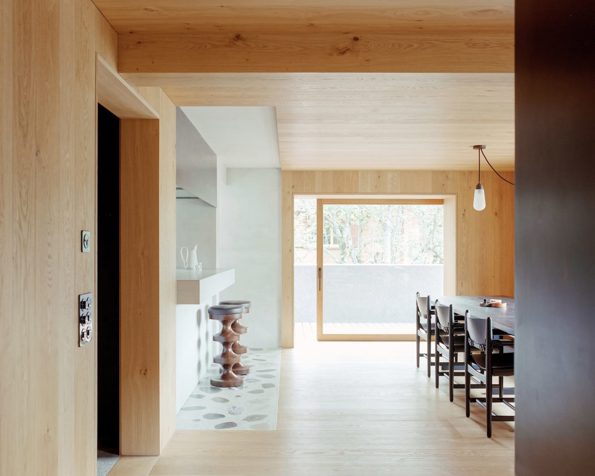 A minimalist open-plan kitchen dining room featuring wooden details and a spacious layout.