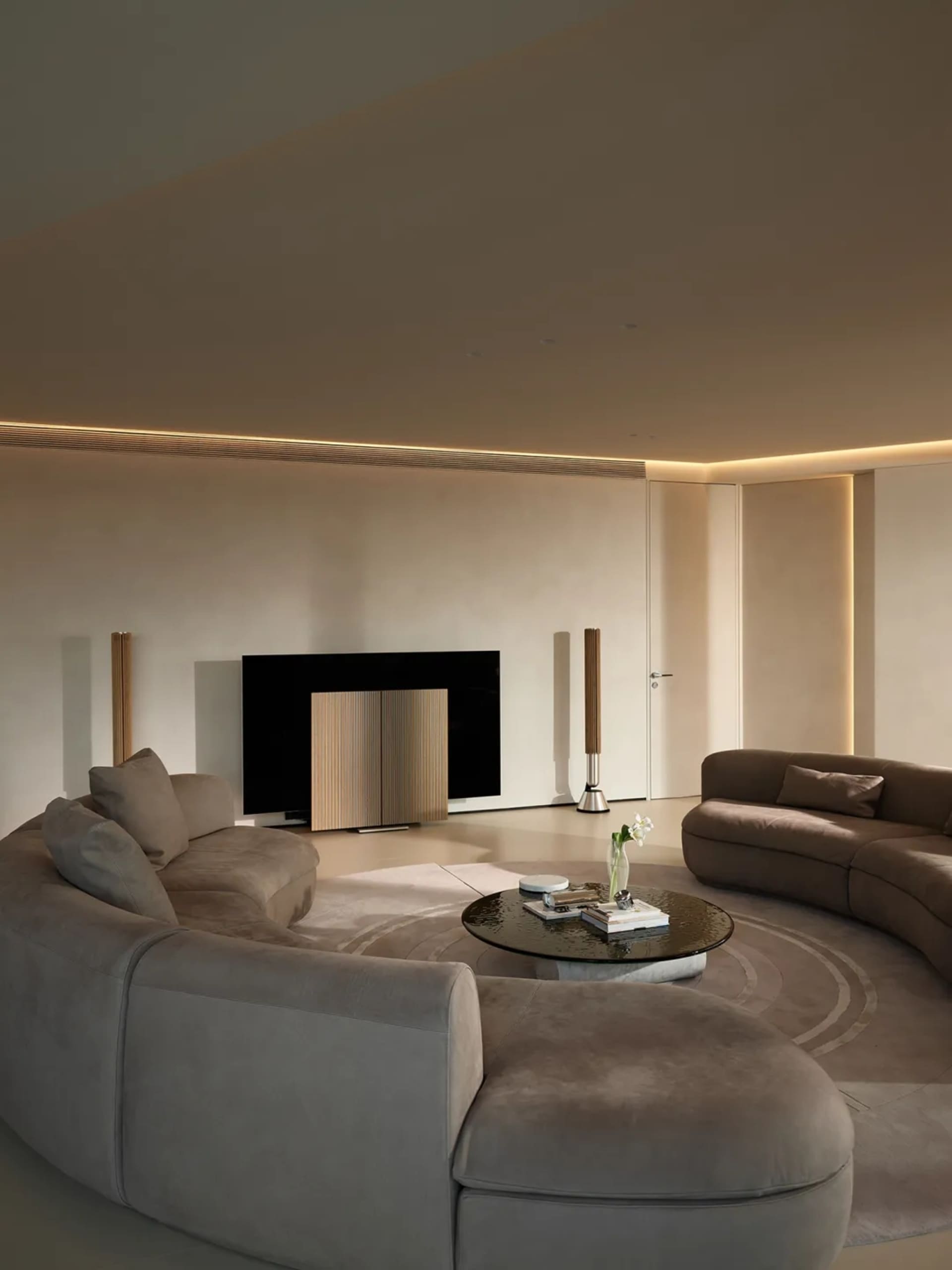 Modern residential interior featuring taupe-colored plush sectionals and wooden fixtures.