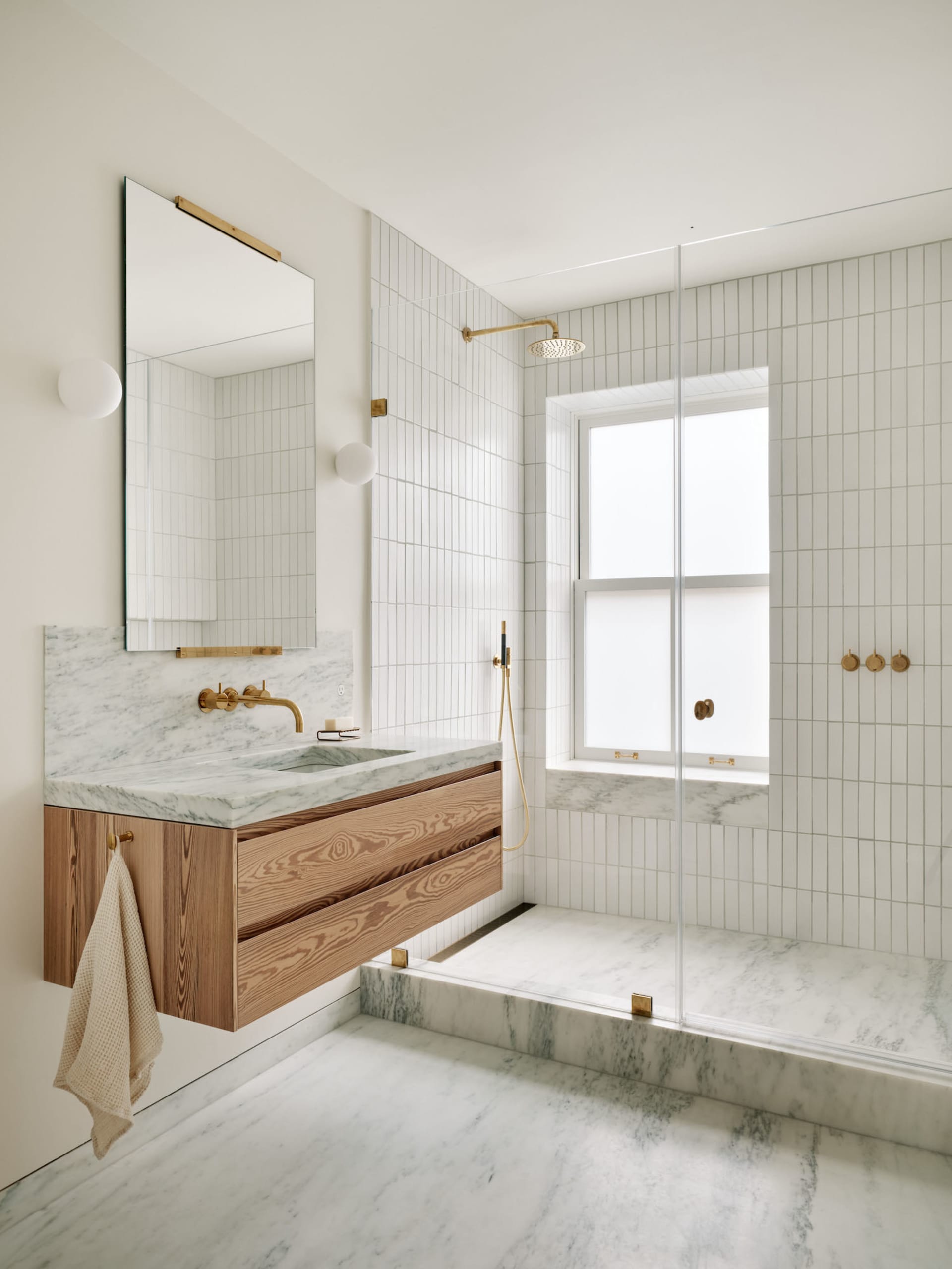 Modern minimalist bathroom with marble flooring, white walls, and wood vanity.