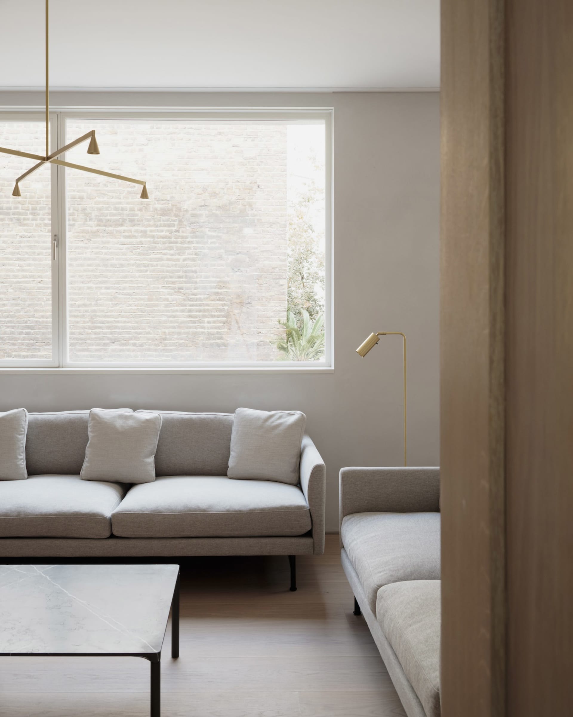 A modern minimalist living room with gray fabric sofas, a marble coffee table, and a floor lamp.