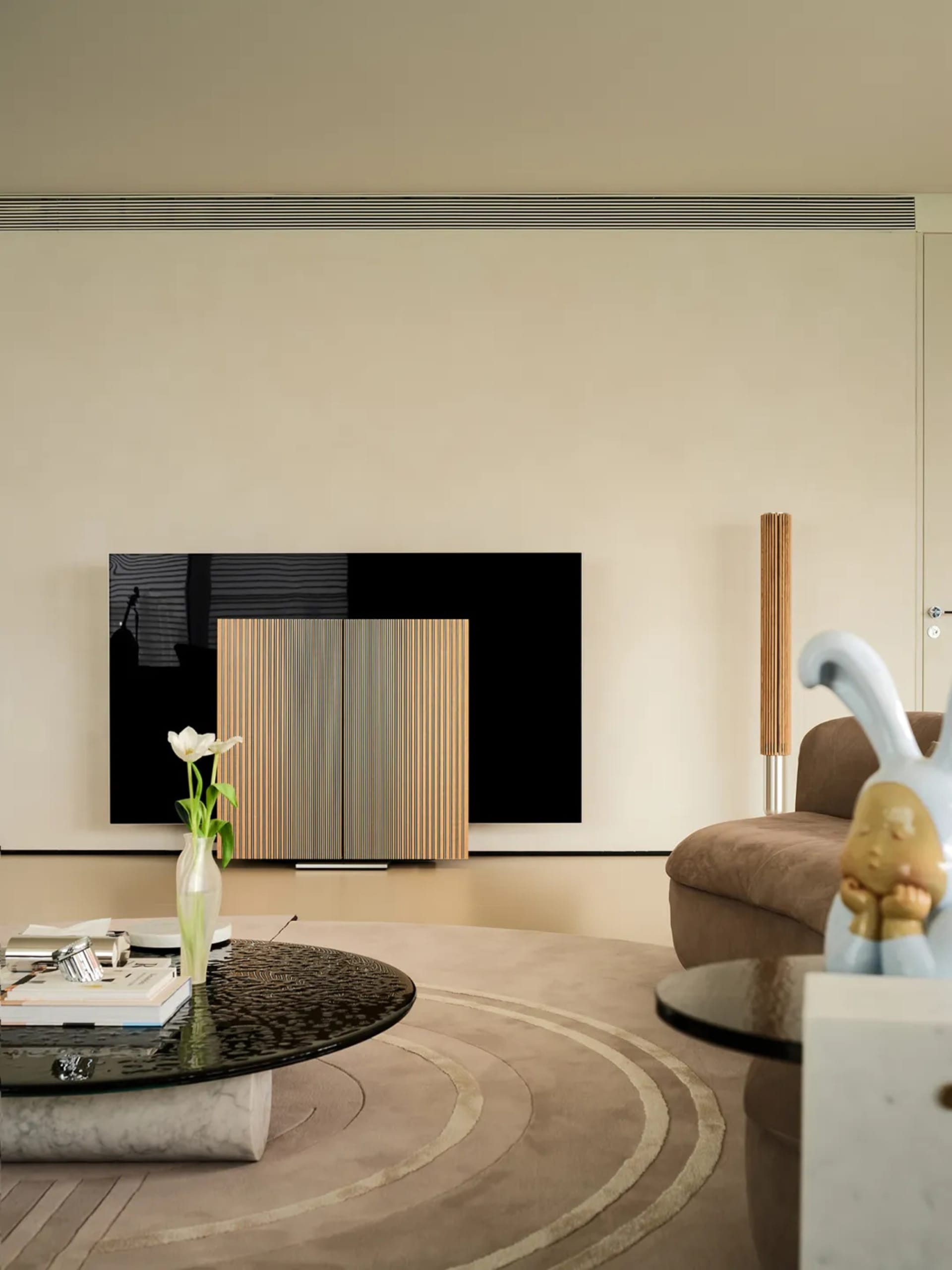A modern living room with marble flooring, a wooden cabinet, and a sleek black TV.