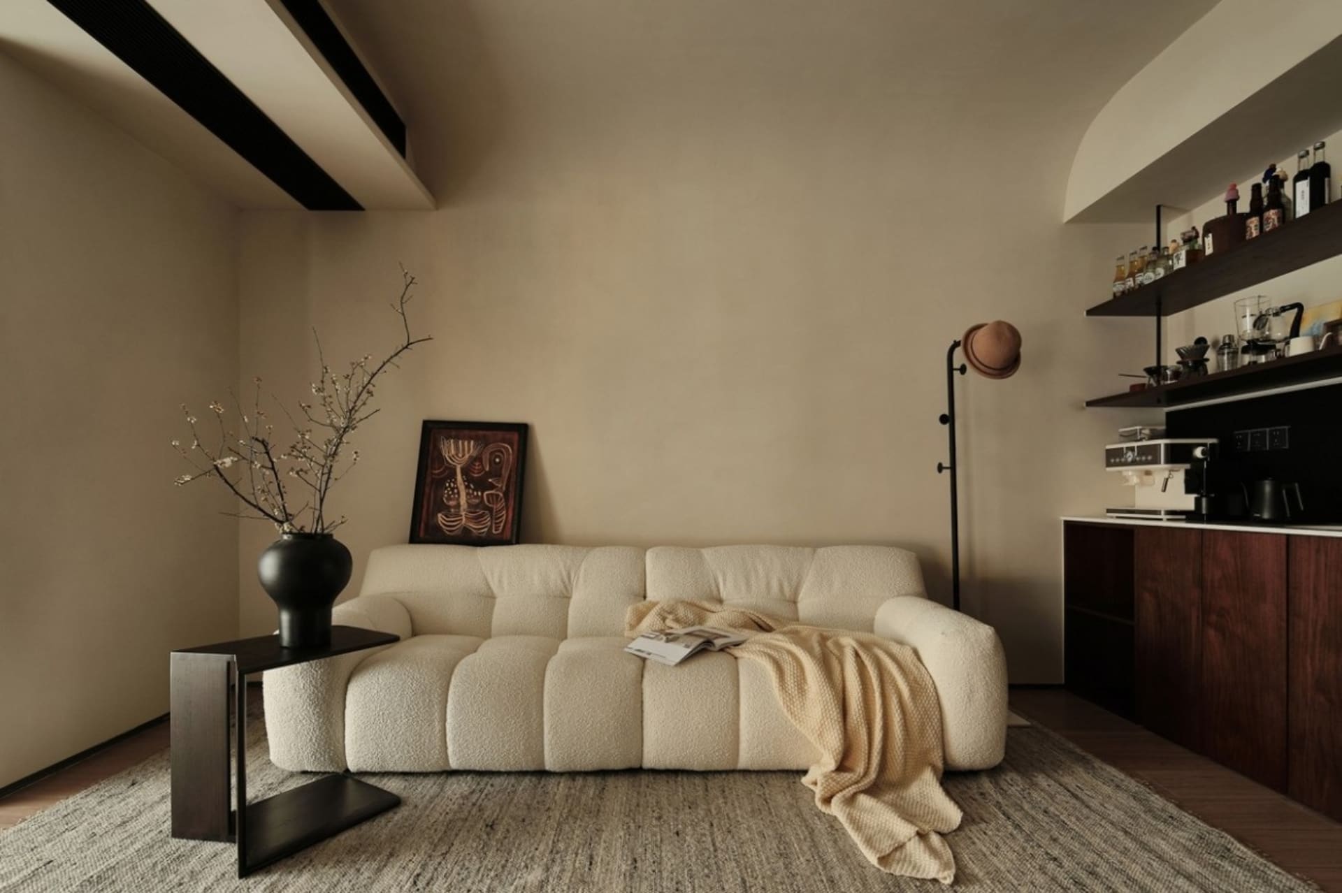 Minimalist living room with a neutral color palette featuring a plush, textured sofa, wooden coffee table, and modern lightin