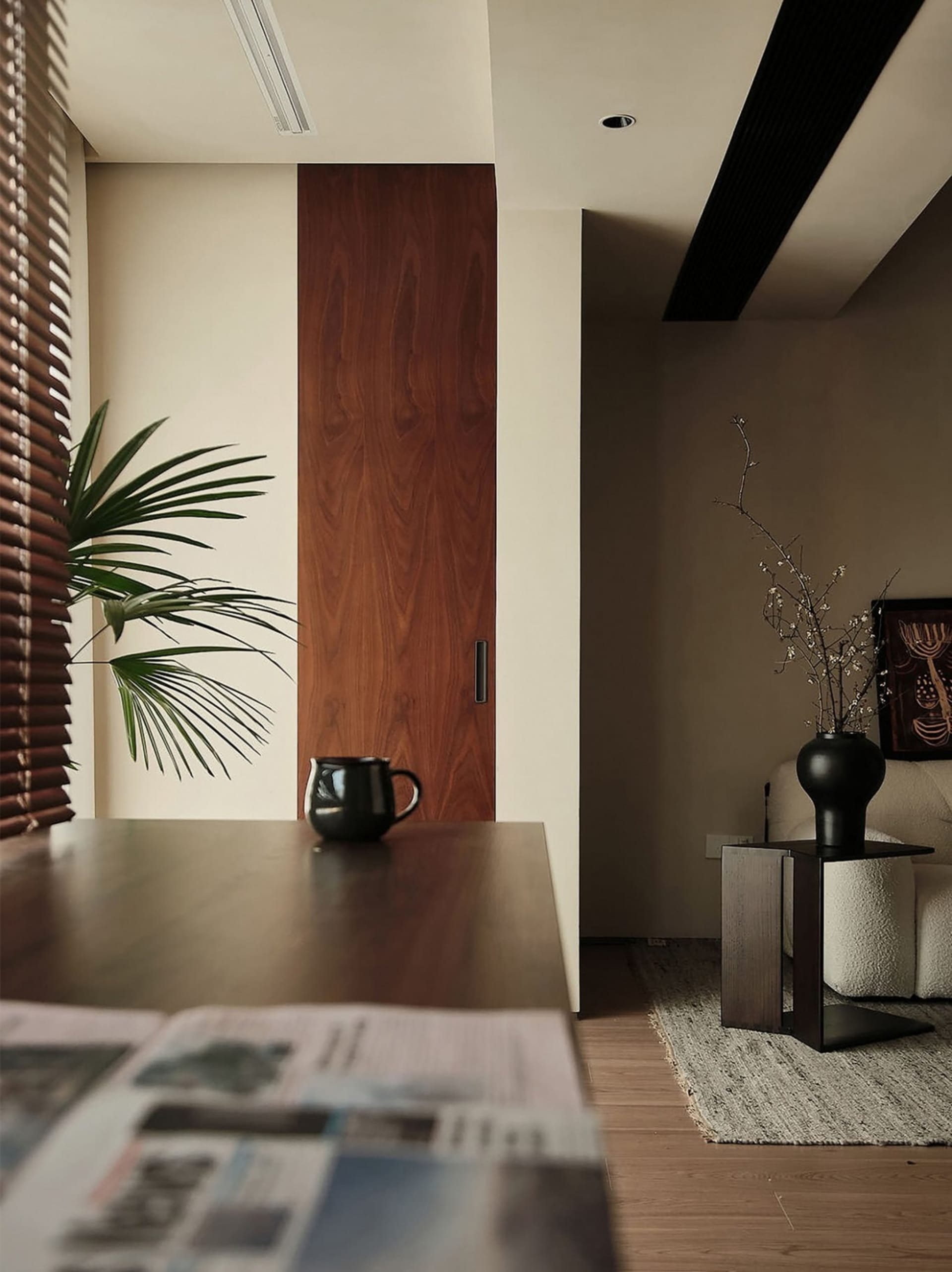 A modern minimalist apartment with wooden doors, fabric seating, and metal accents.