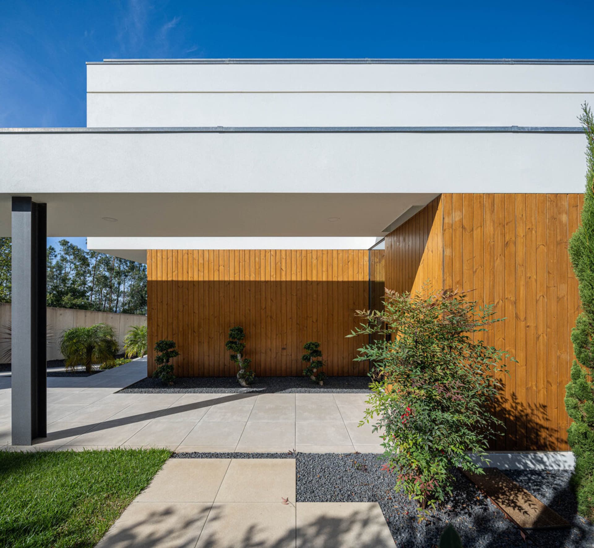 Modern minimalist house with white facade, wooden panels, and glass windows.