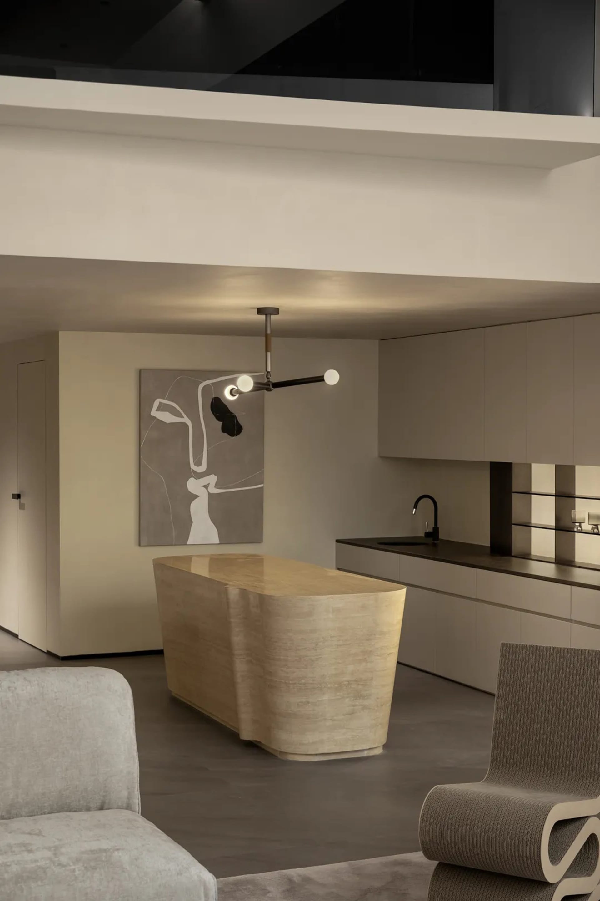 A contemporary kitchen featuring a sleek marble island with a geometric design, surrounded by minimalist cabinetry and a hang