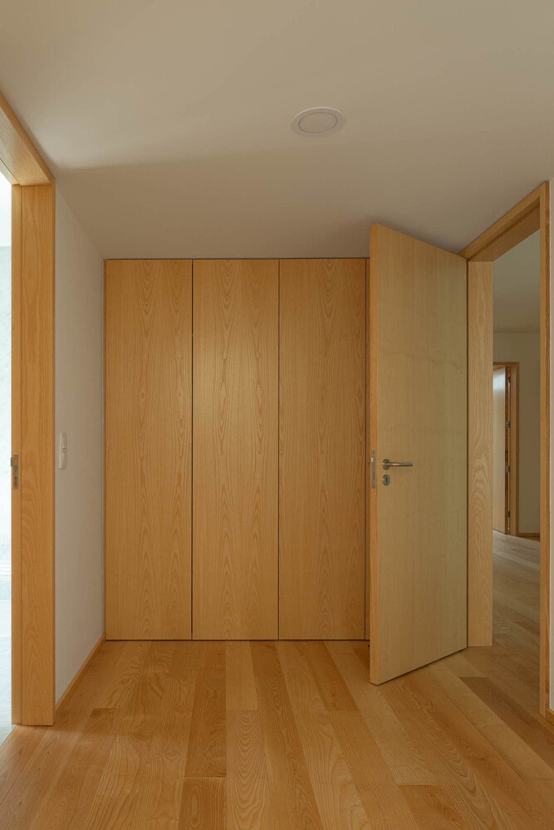 A modern minimalist closet with wooden doors.