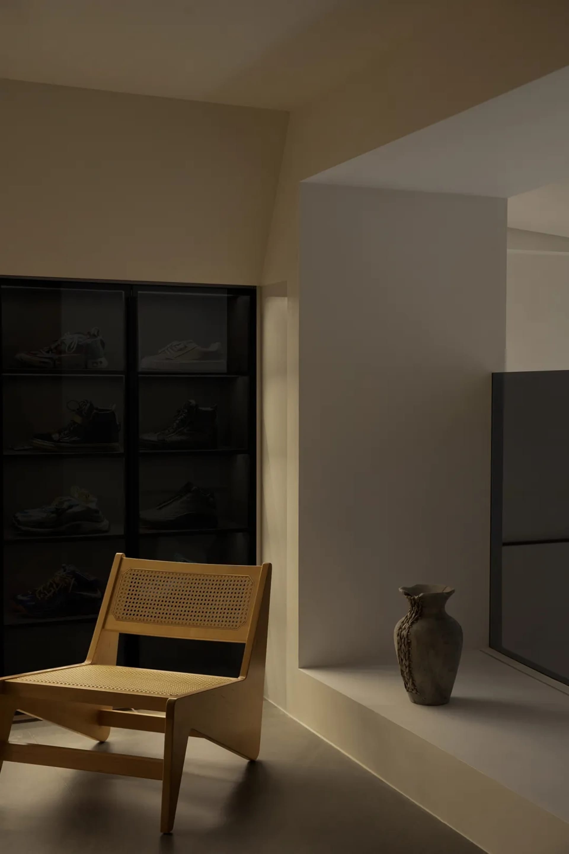 Contemporary minimalist room with a corner display of glass-encased sneakers.