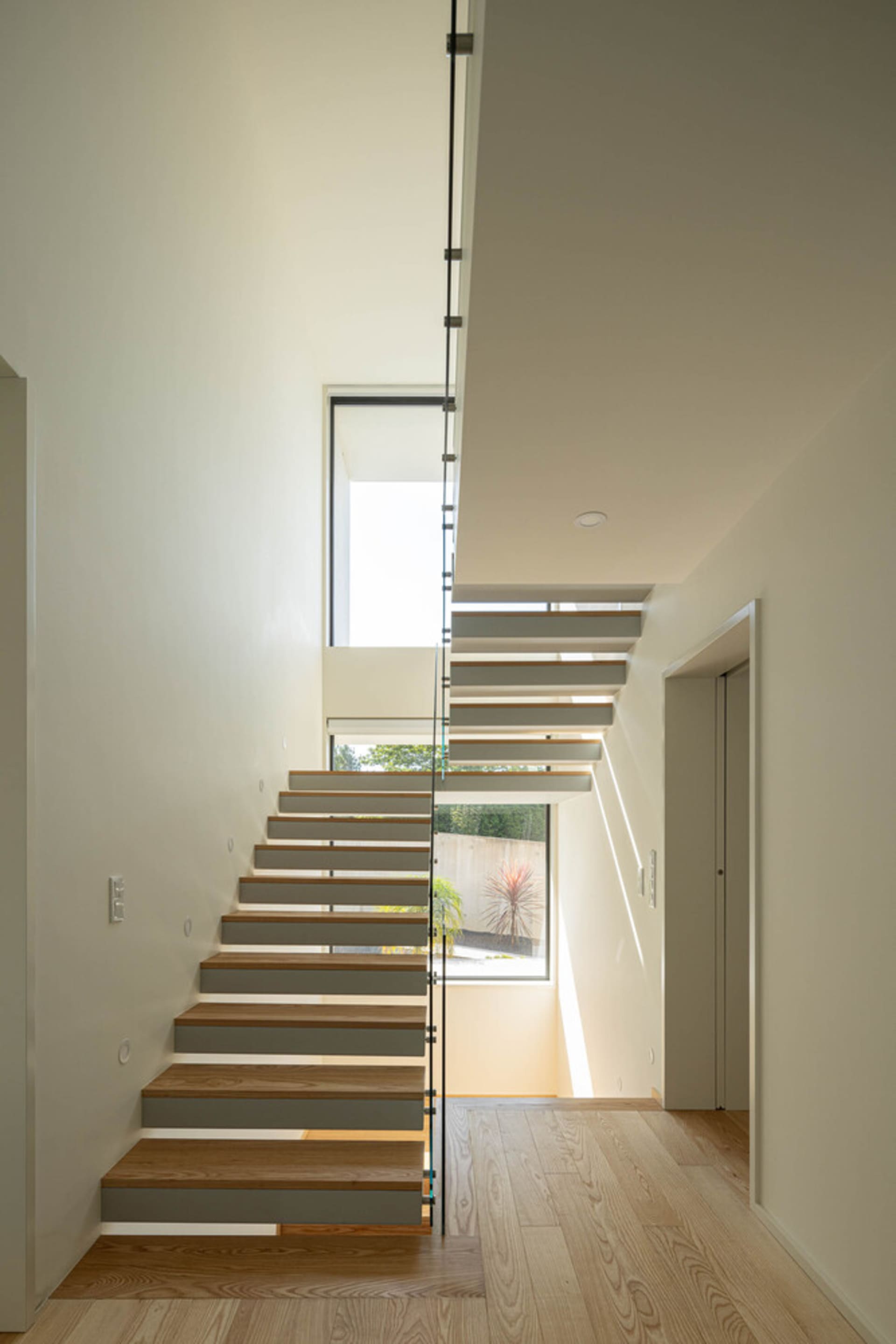 A modern staircase with wooden steps and glass railing.