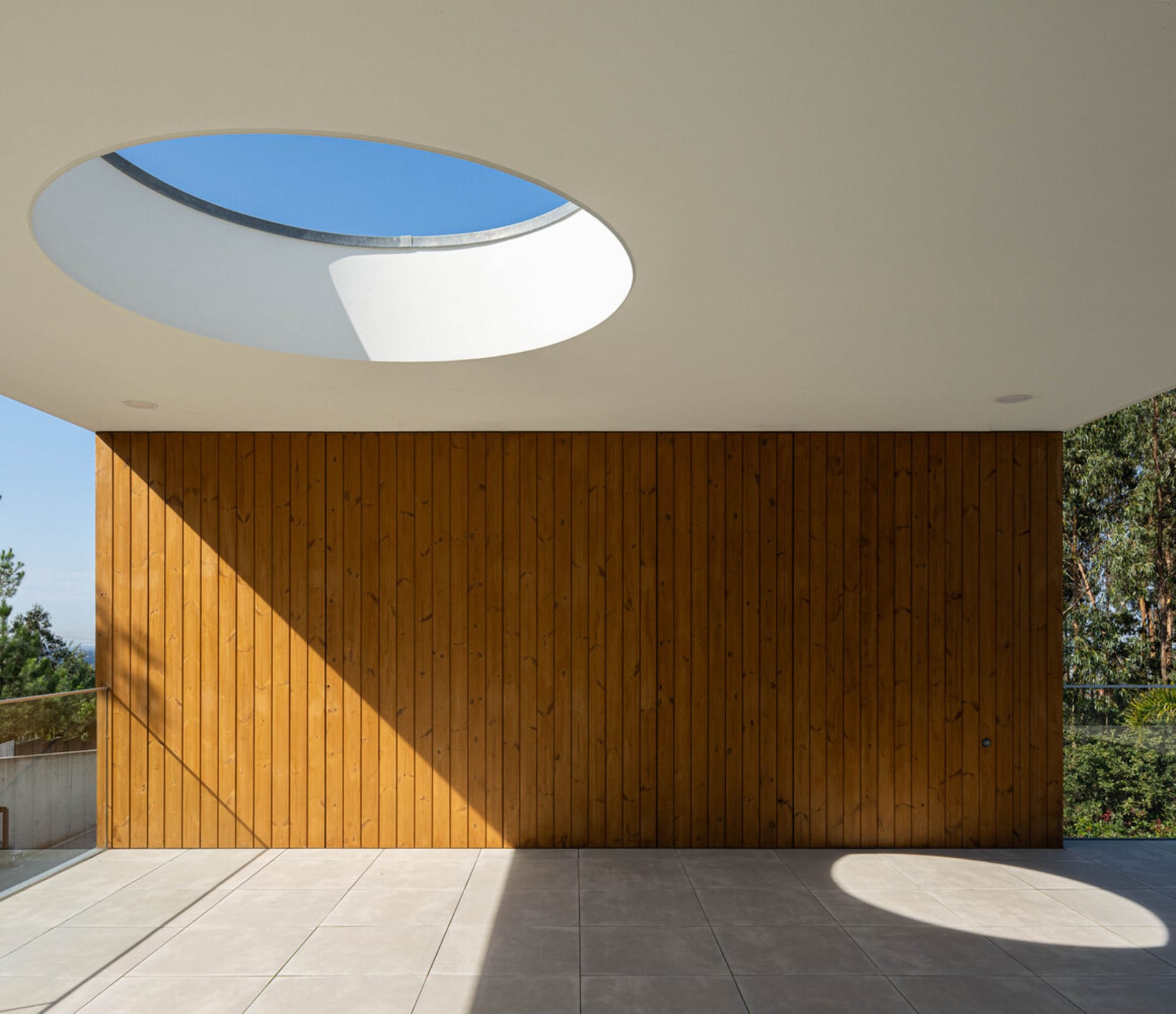 Modern wooden exterior with a geometric design featuring a round skylight and textured wood paneling.