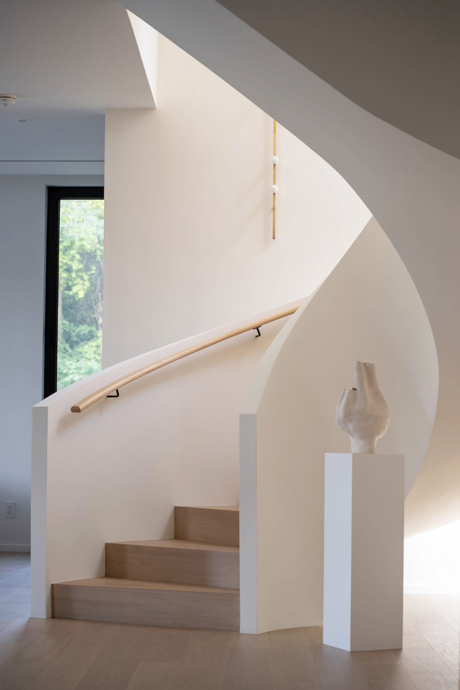A modern staircase with white walls, wood steps, and a wooden handrail.