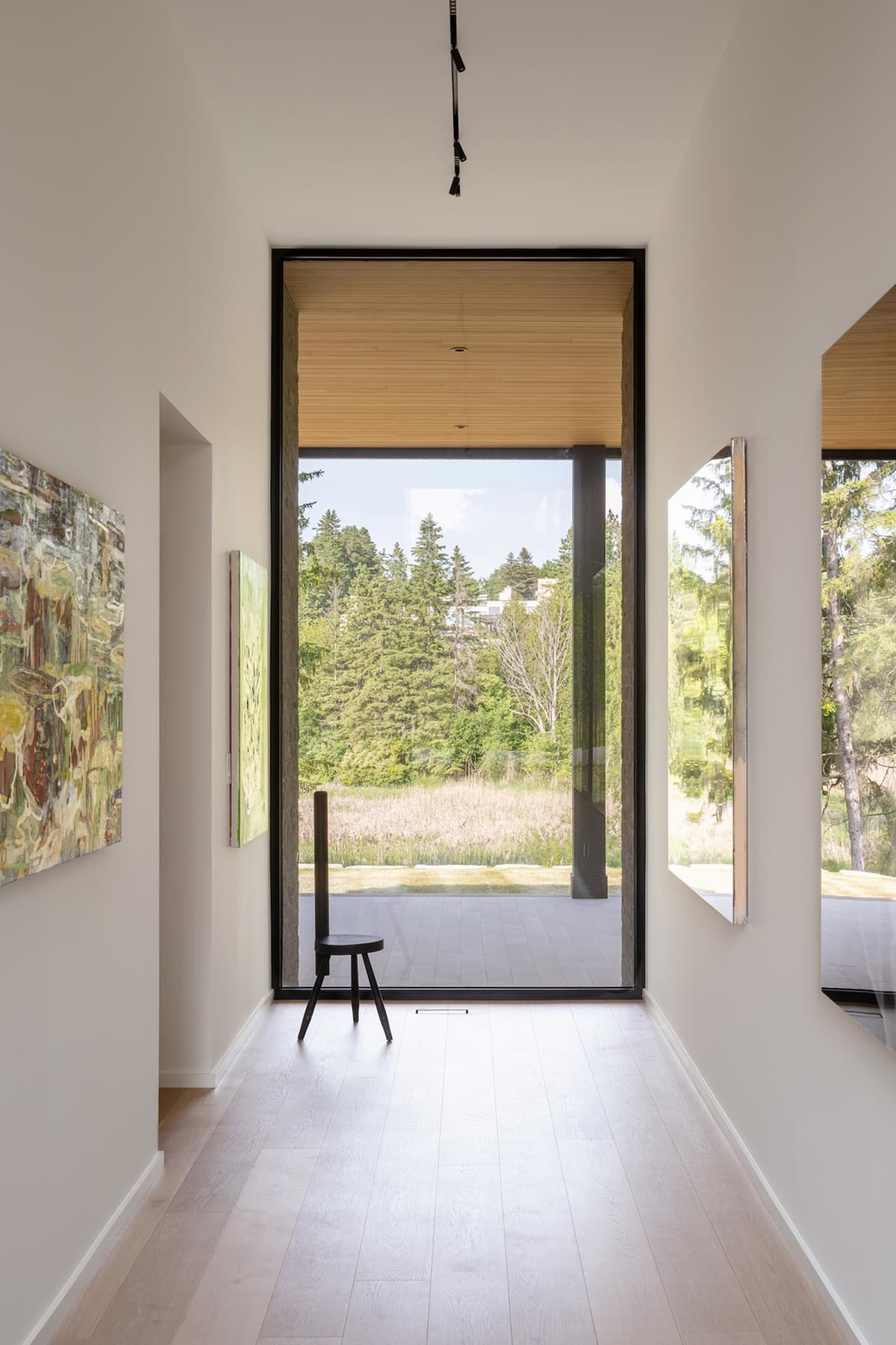 A modern living room with a wooden floor and large window overlooking greenery.