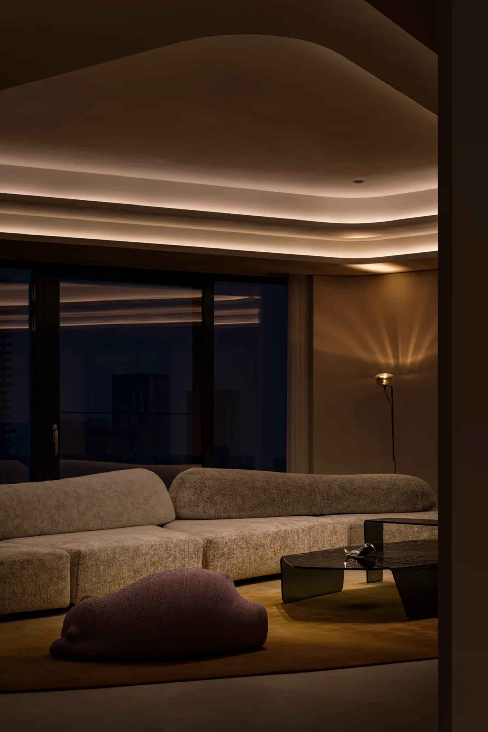 A minimalist residential interior with modern furniture and textured fabric on sofas and cushions.