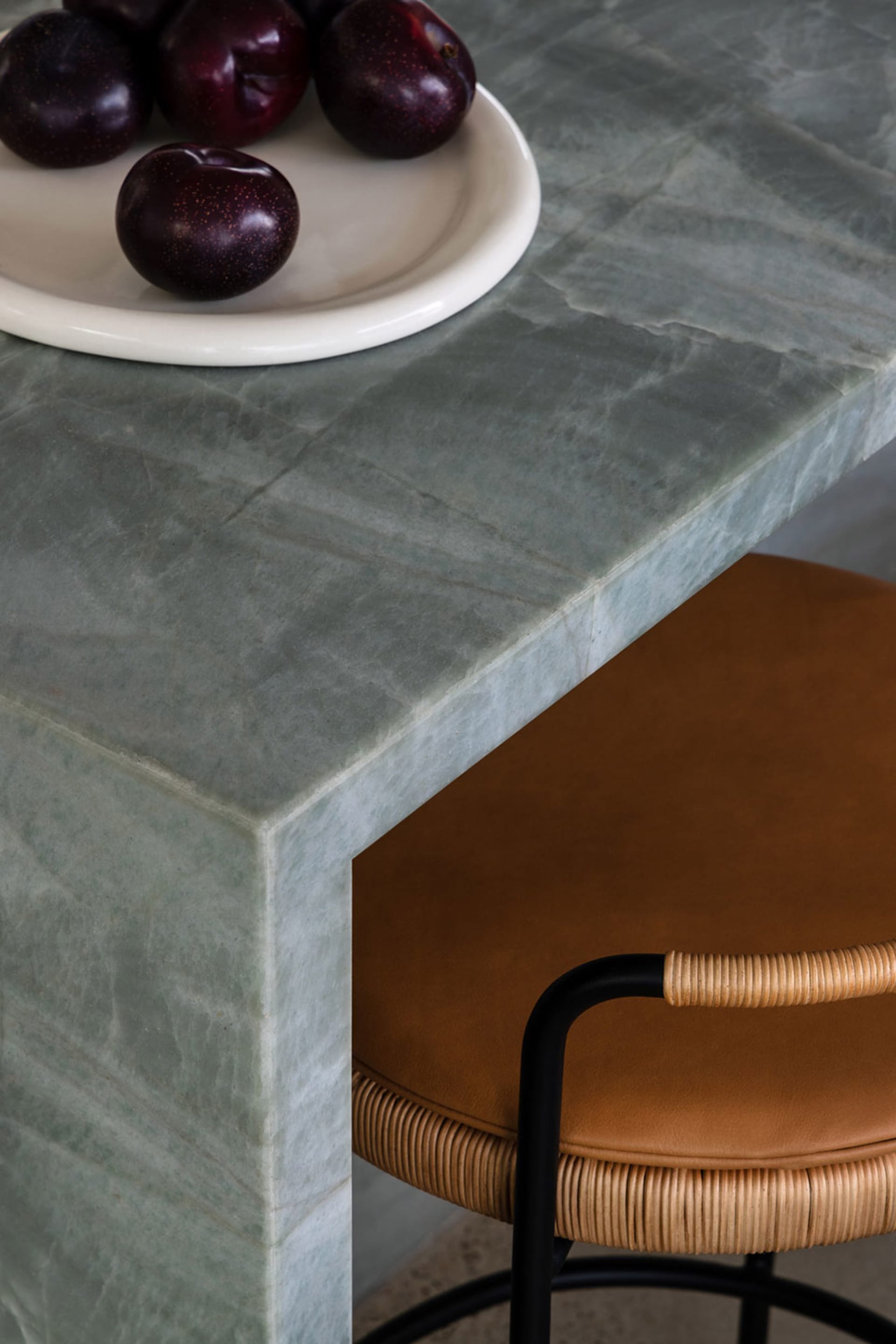 A modern kitchen featuring a marble countertop with plums on a plate.