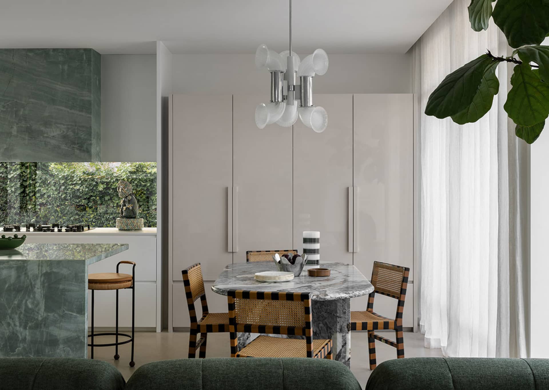 A modern kitchen featuring a distinctive marble dining table surrounded by woven chairs, situated in a contemporary residenti