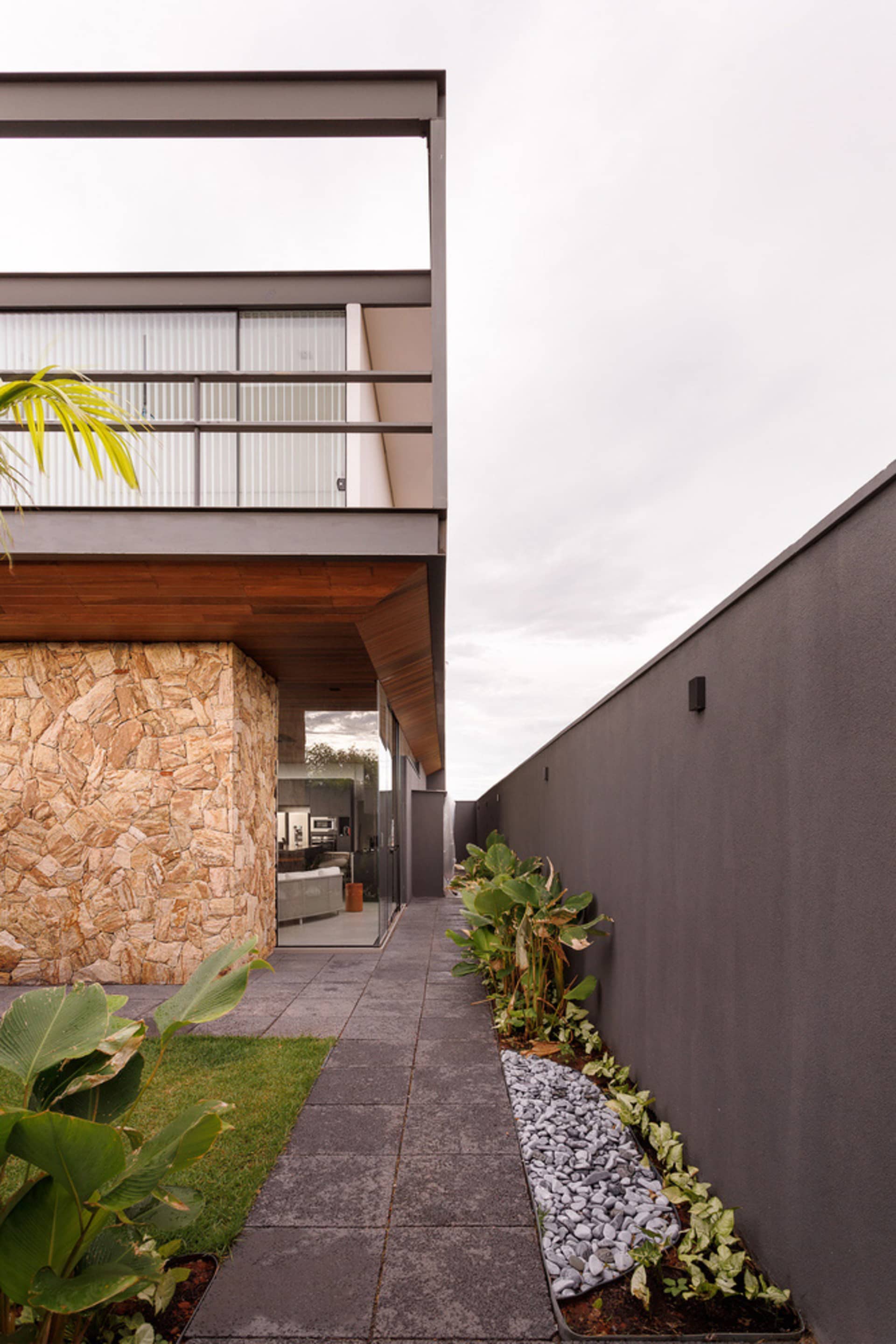 Modern residential exterior featuring concrete, stone, and glass materials.