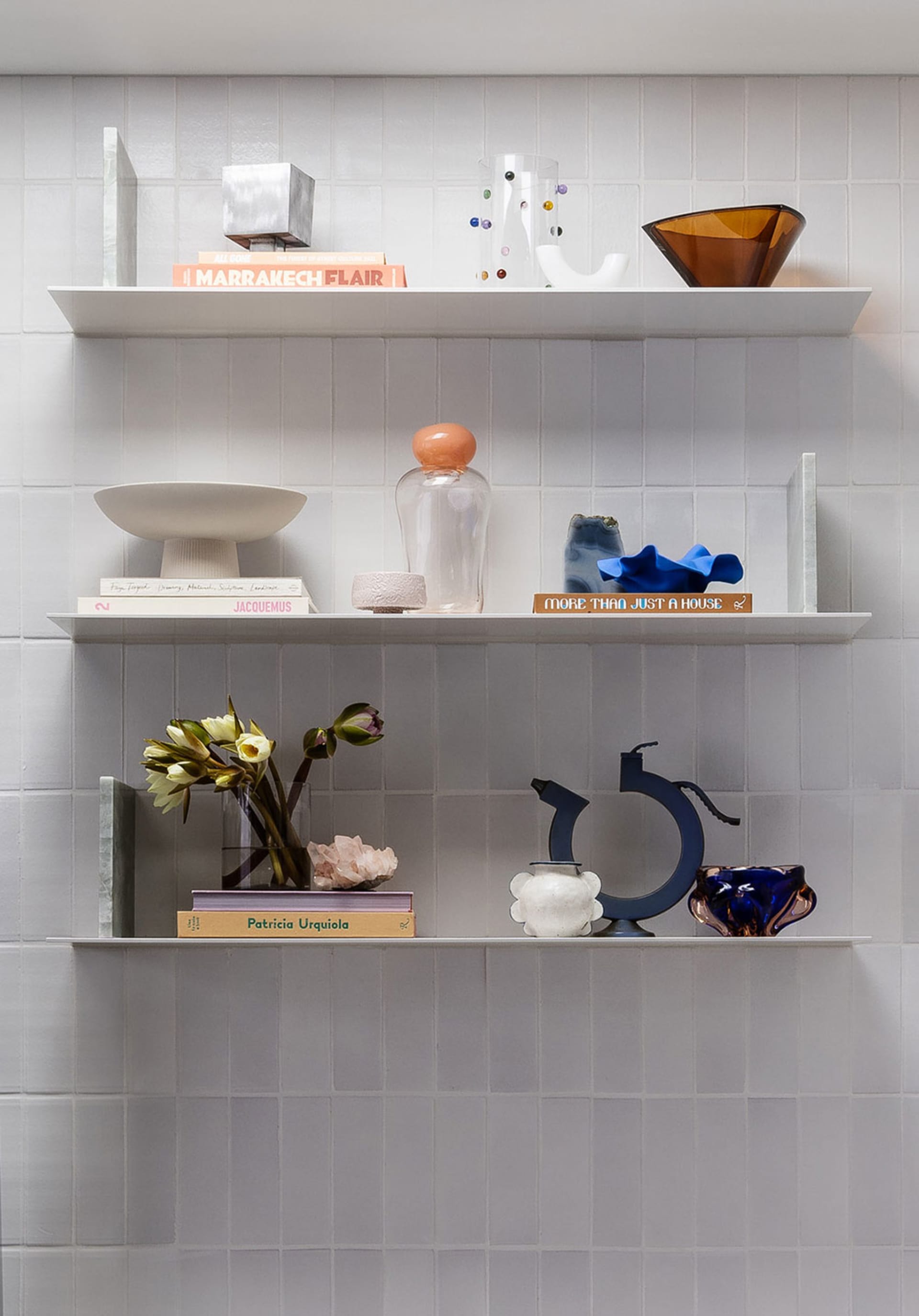 A well-organized shelf featuring ceramic, glass, and metal decorative items.