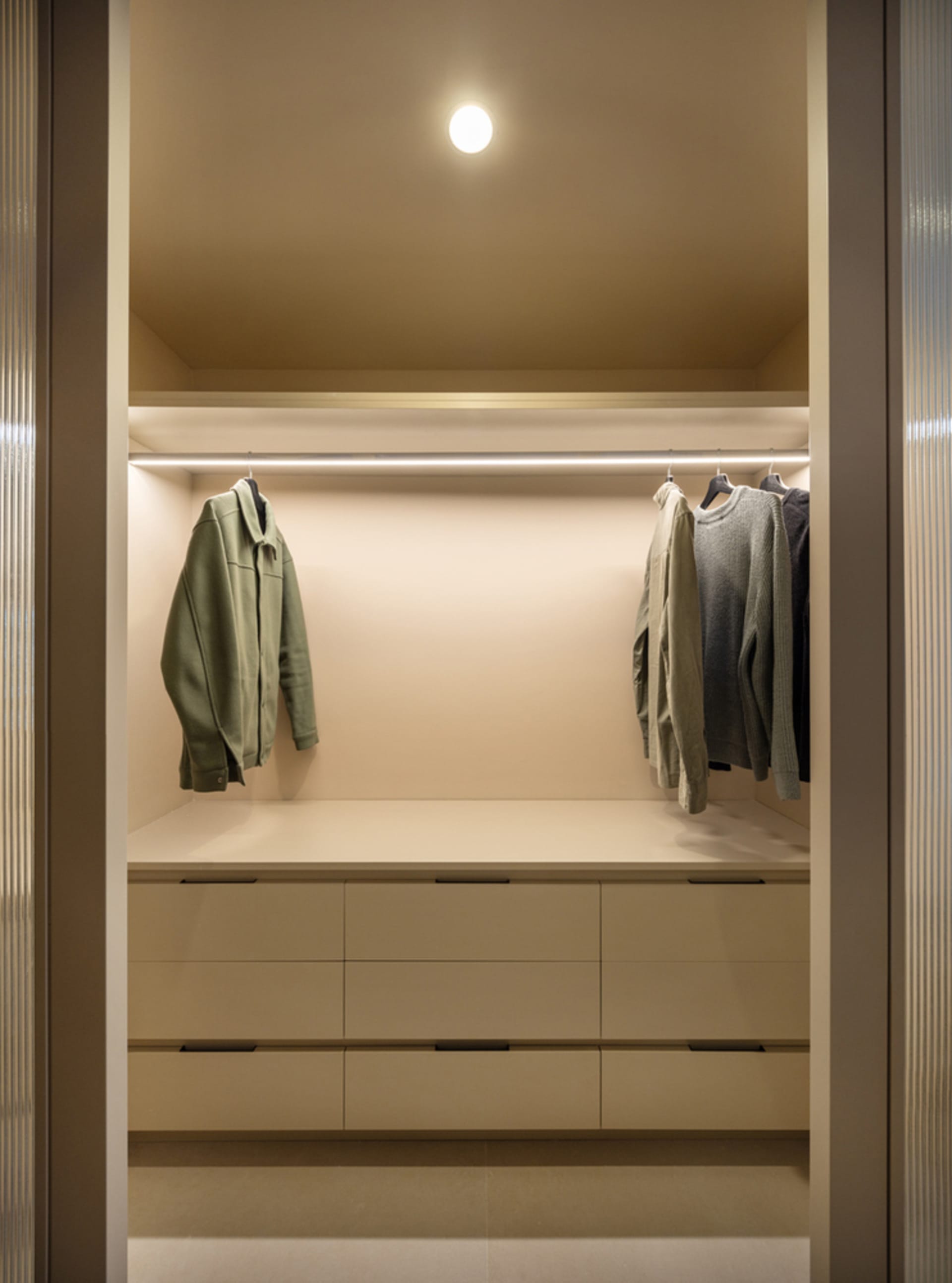 Modern closet with neutral color palette, featuring floating shelves and clothing storage.