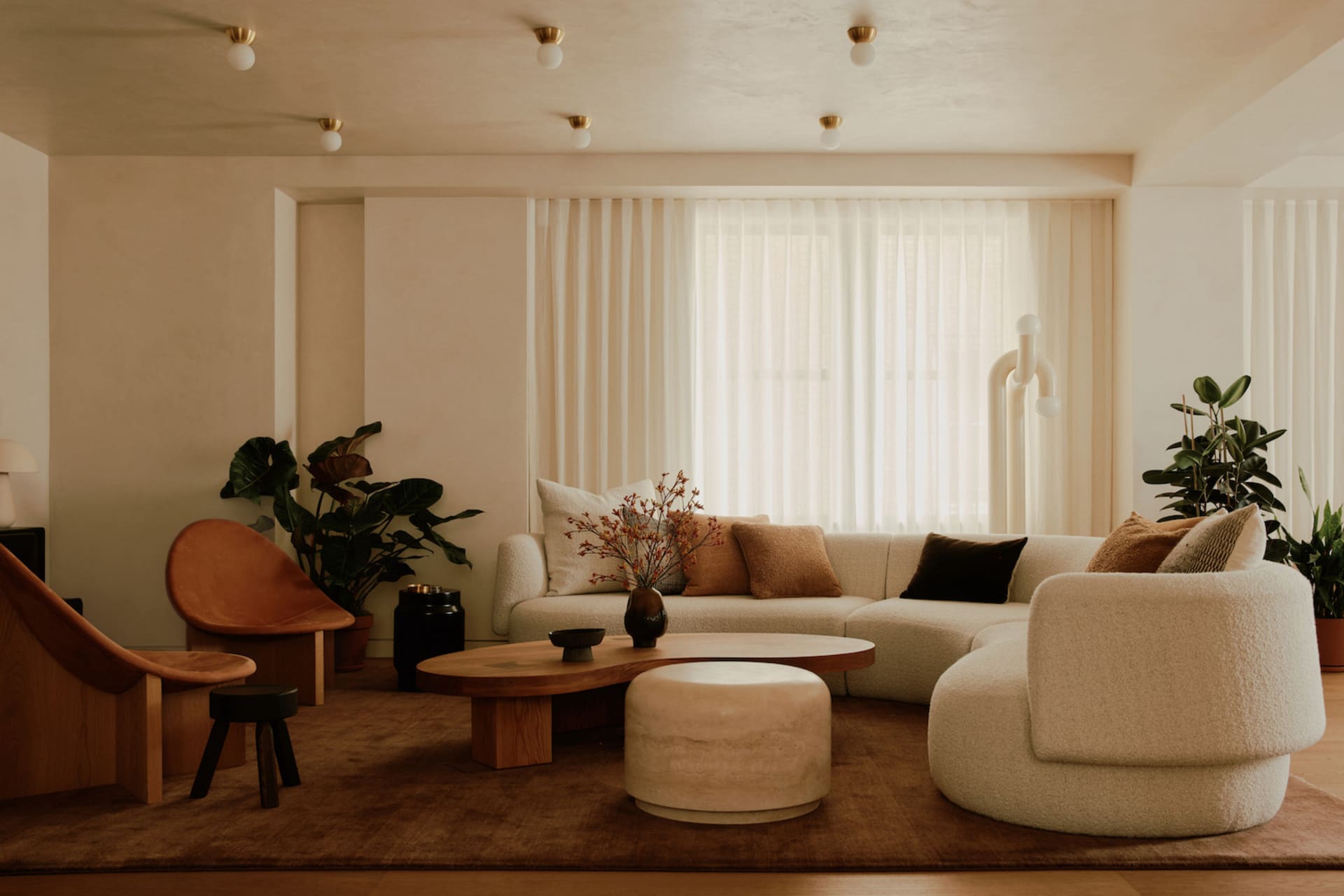 Modern minimalist living room with mid-century wood and fabric elements, featuring a large sofa, coffee table, and decorative