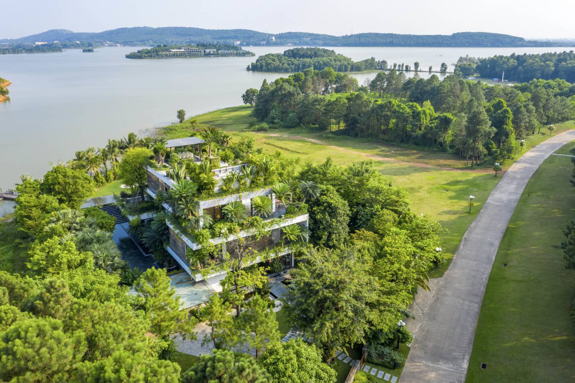 Modern residential building surrounded by lush greenery with a rooftop terrace