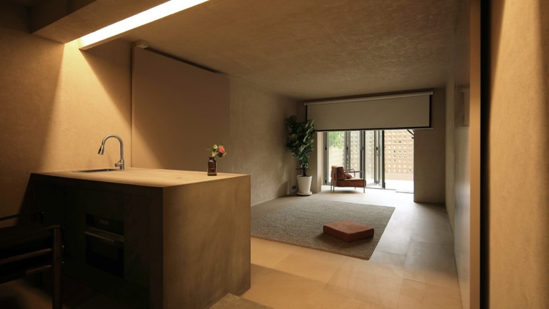 A minimalist residential kitchen with concrete cabinets, wooden flooring, and glass windows.