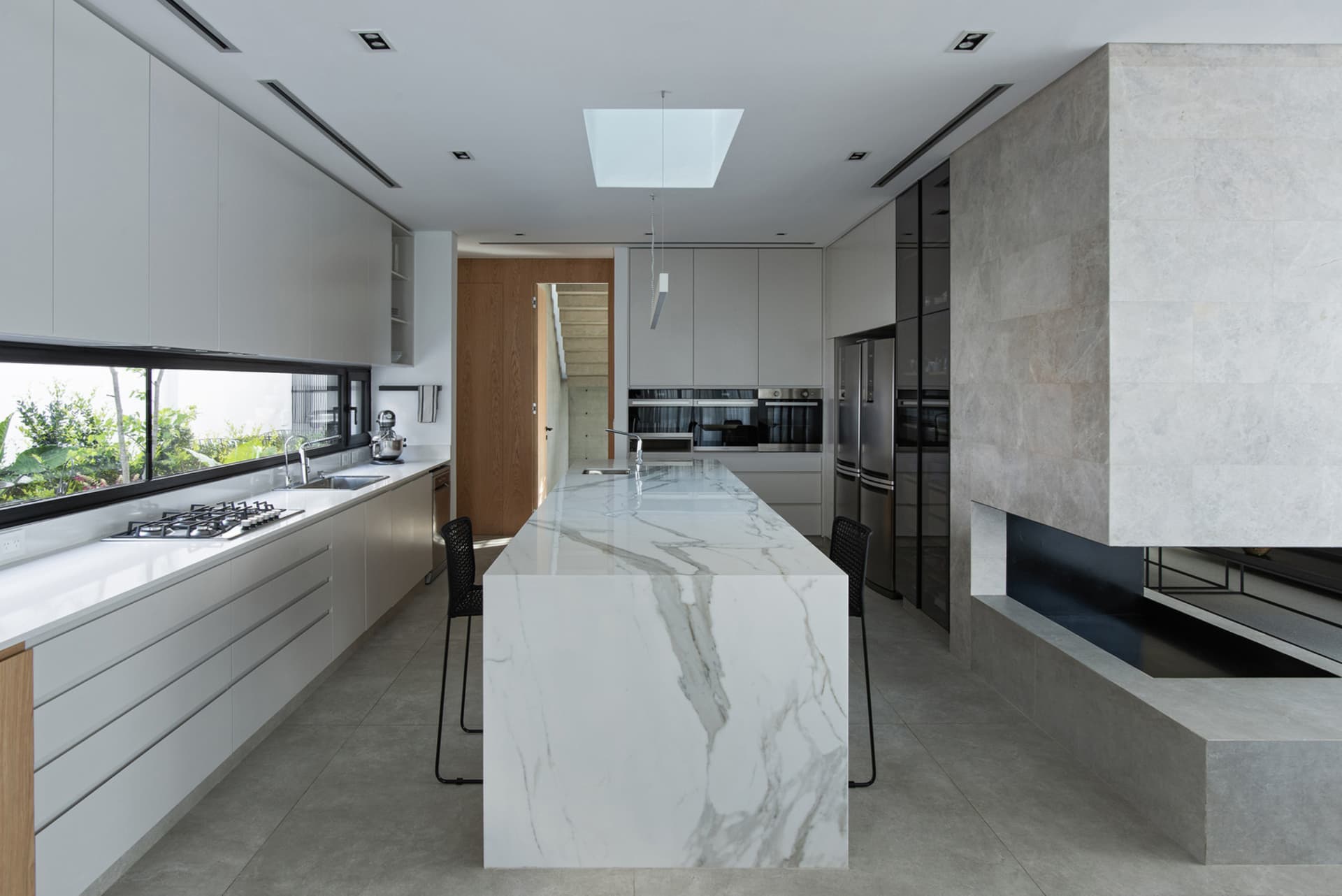 A modern kitchen featuring a marble island, stainless steel appliances, and ample counter space.