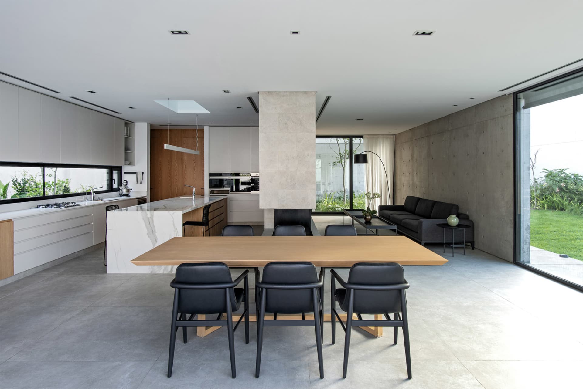 Modern minimalist living dining kitchen space with concrete, marble, and metal materials