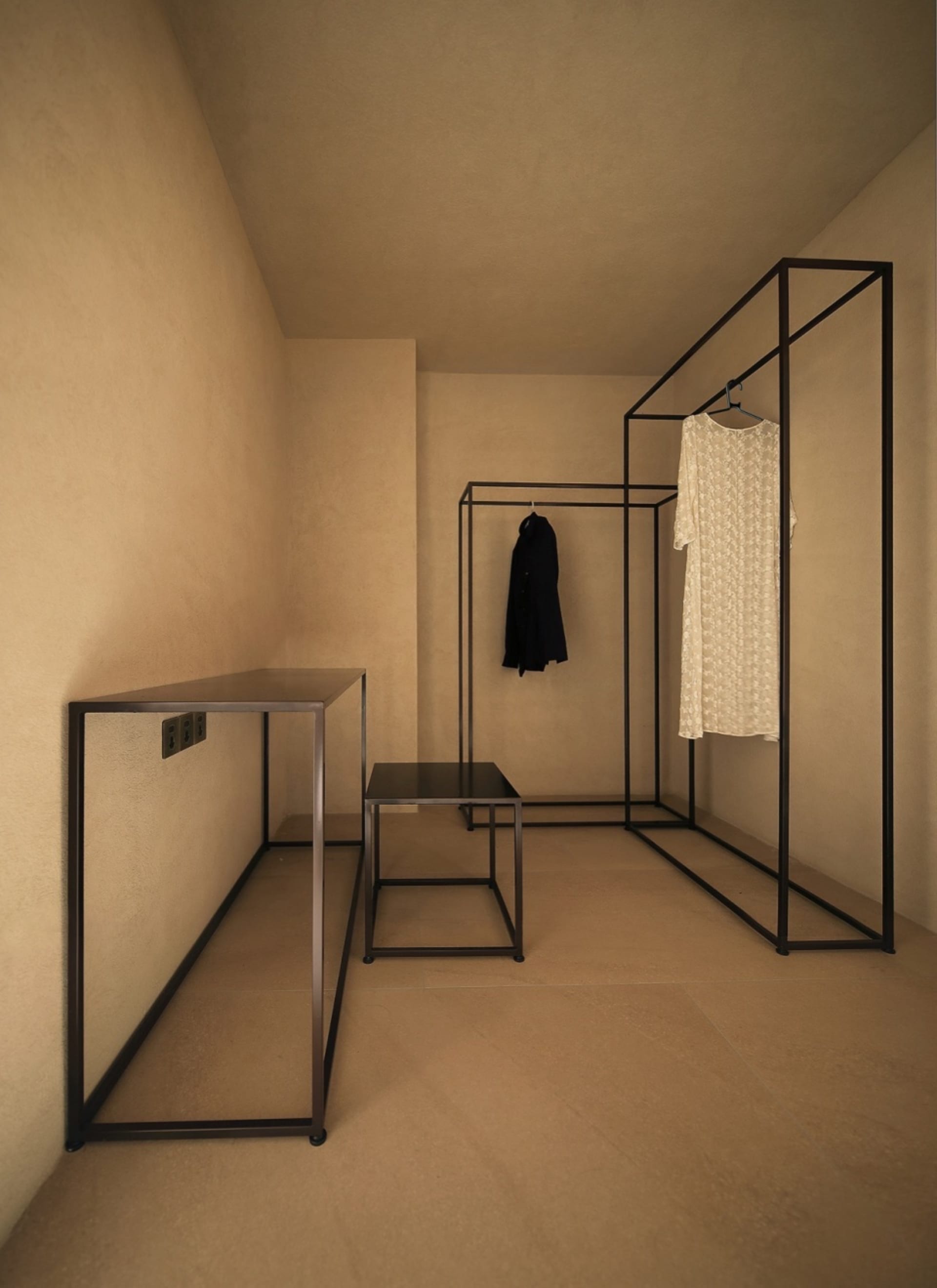 A minimalist clothing display area featuring a metal and glass structure.