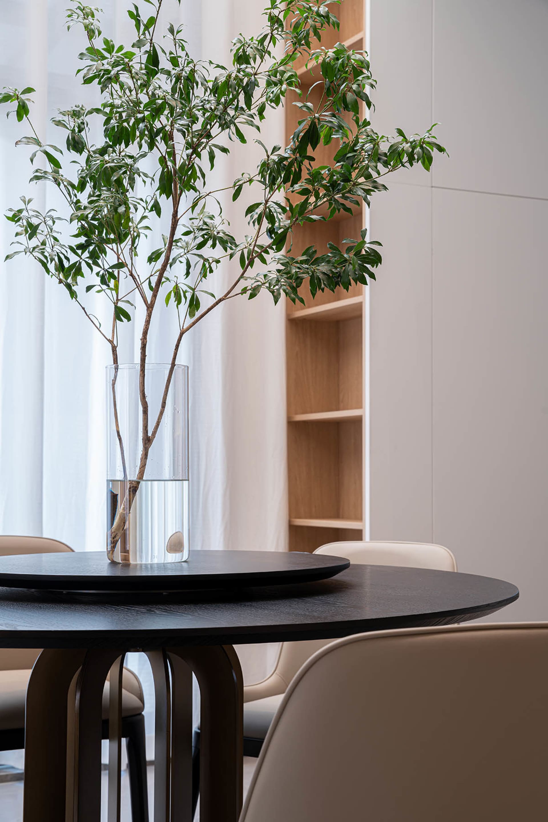 A modern interior design featuring a wooden table with a vase of greenery on top.