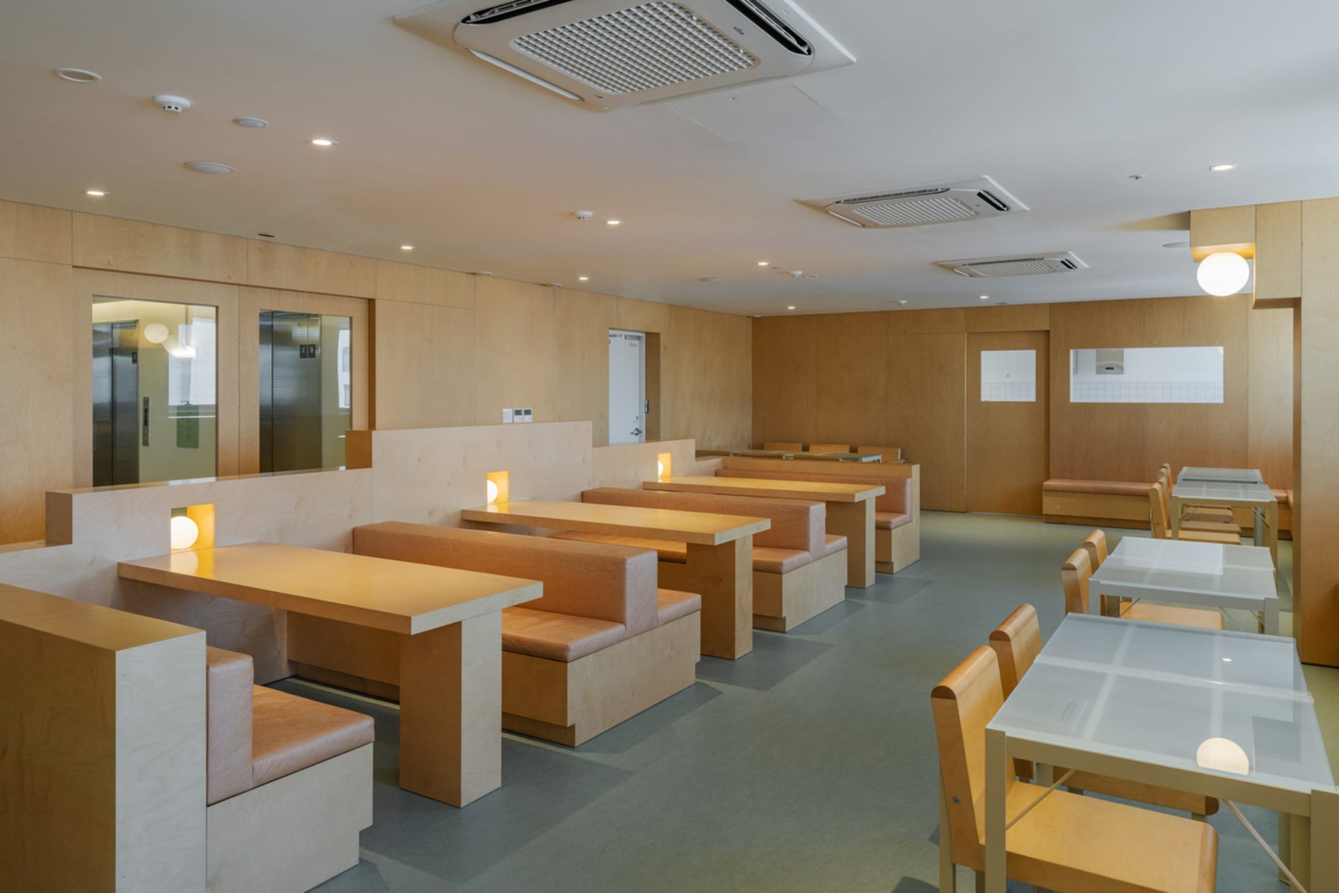 現代自助餐廳內擺放木質桌椅與長椅,線條簡潔,呈現極簡美學。