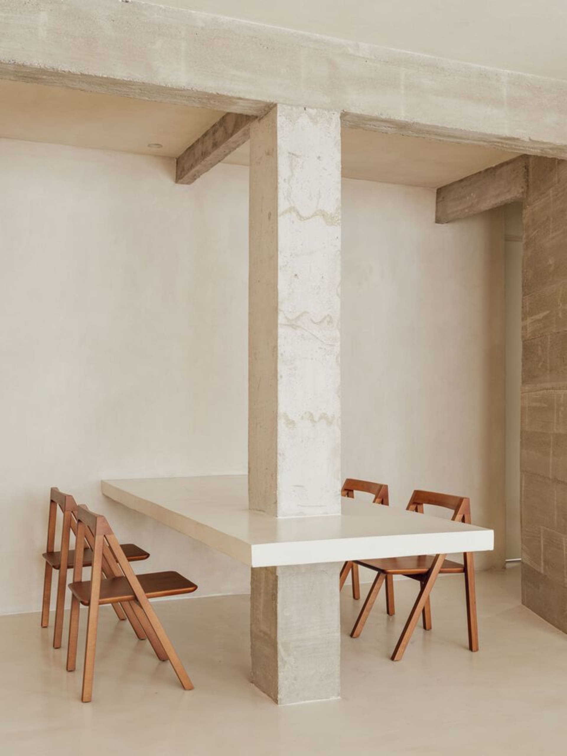 Modern minimalist dining room with concrete table and wooden folding chairs.
