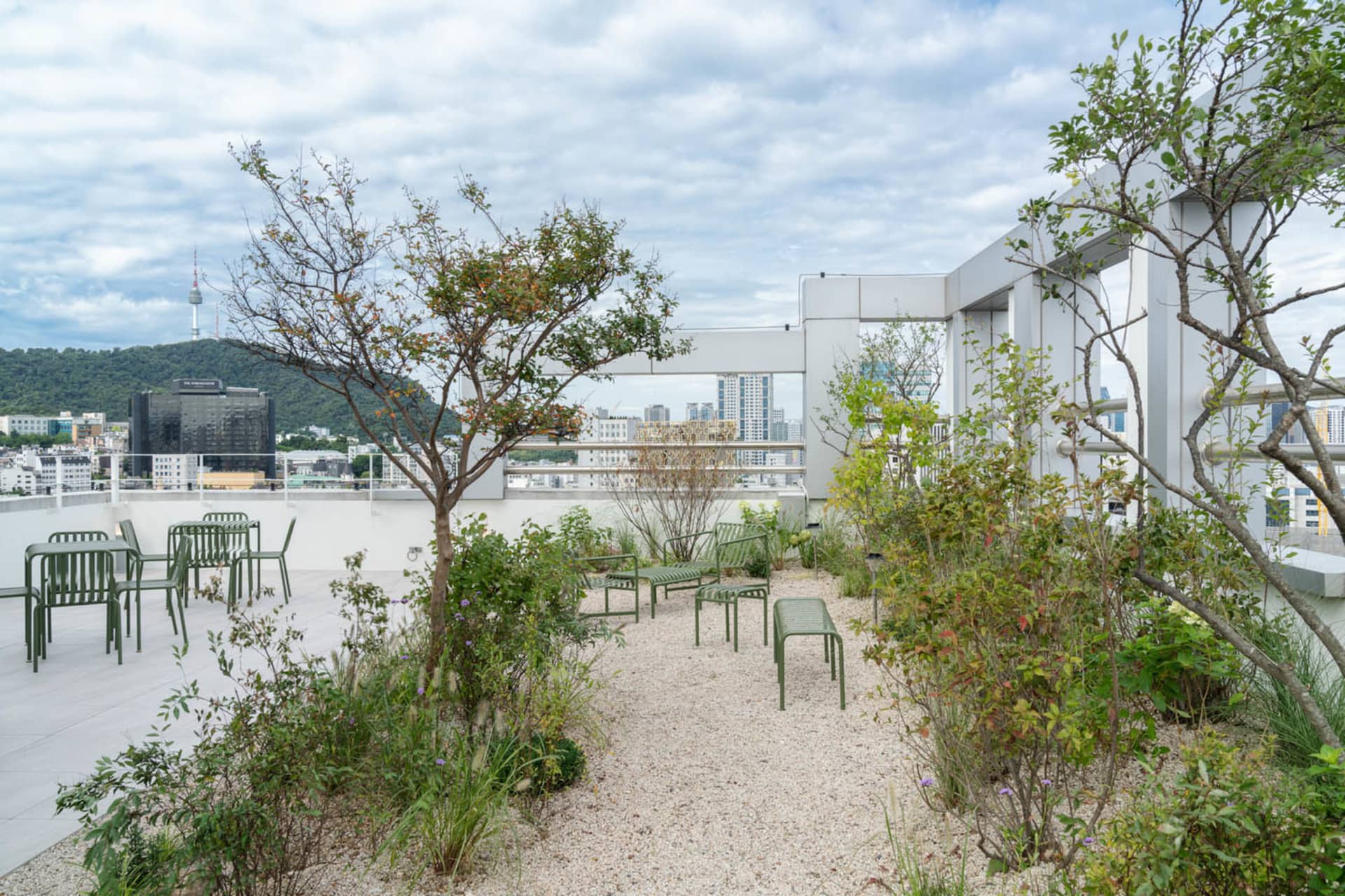 Outdoor space with concrete ground, trees, and plants on a rooftop