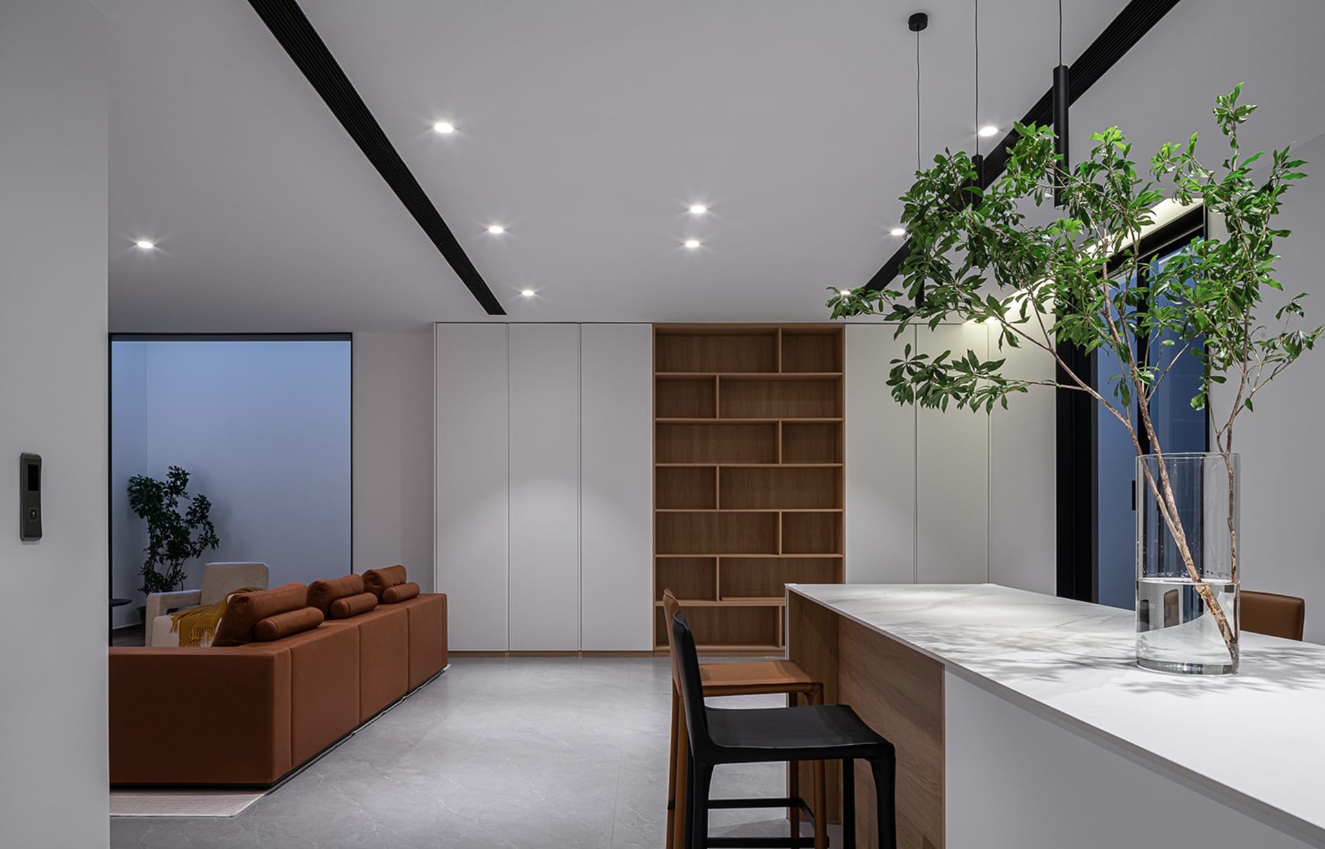 Modern, open-plan kitchen with white walls, wooden accents, and black seating.